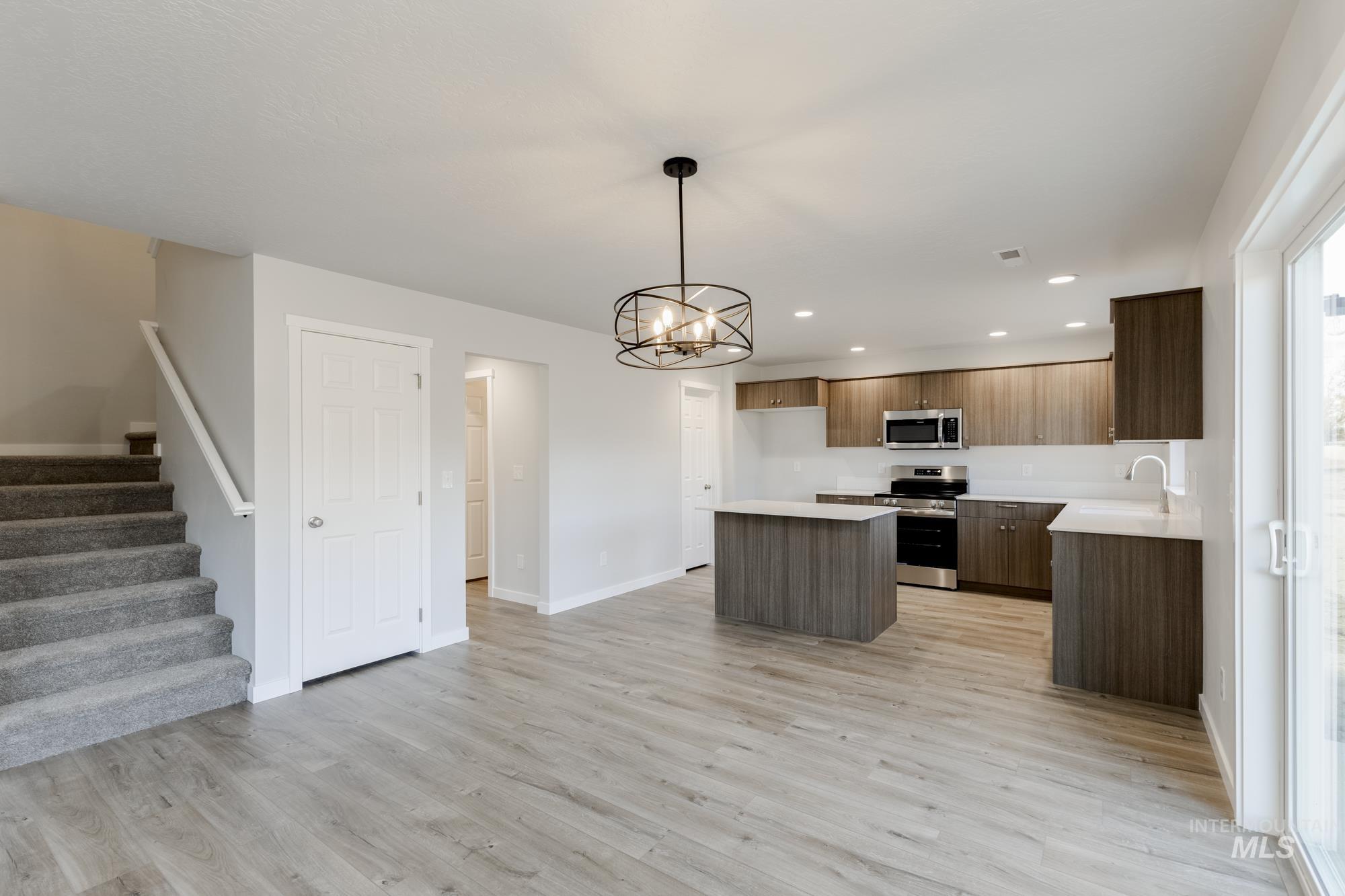Kitchen with a center island, light countertops, appliances with stainless steel finishes, hanging light fixtures, and a chandelier