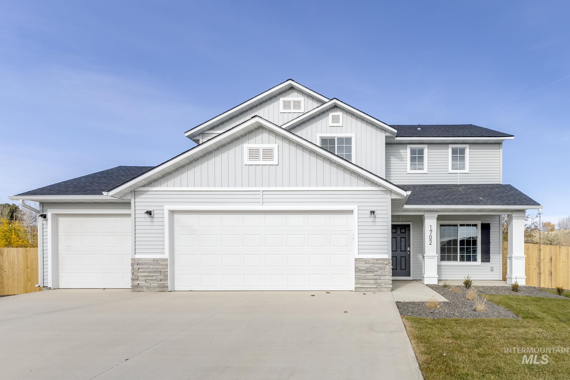 View of front of property featuring a shingled roof, stone siding, board and batten siding, concrete driveway, and a porch