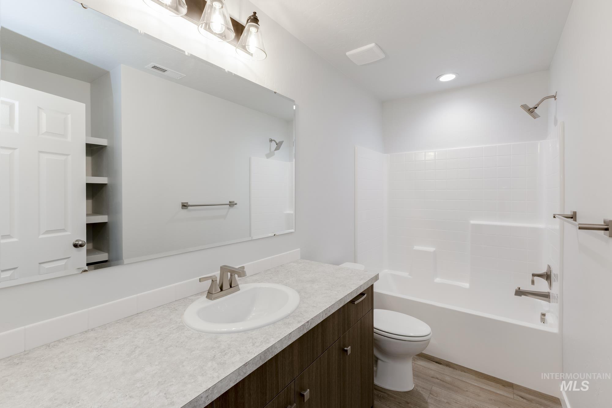 Bathroom with vanity, shower / tub combination, and light wood finished floors