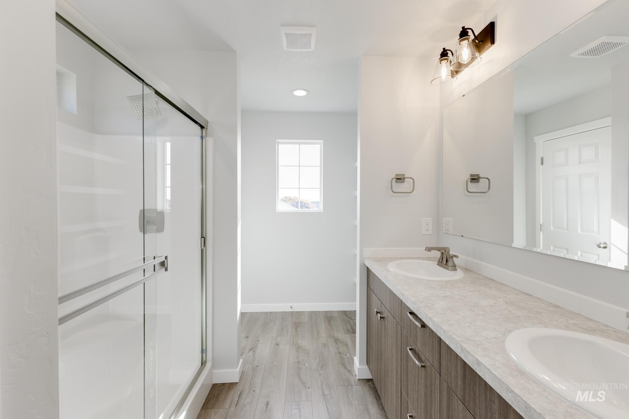 Full bath featuring a shower stall, double vanity, light wood-style floors, and recessed lighting