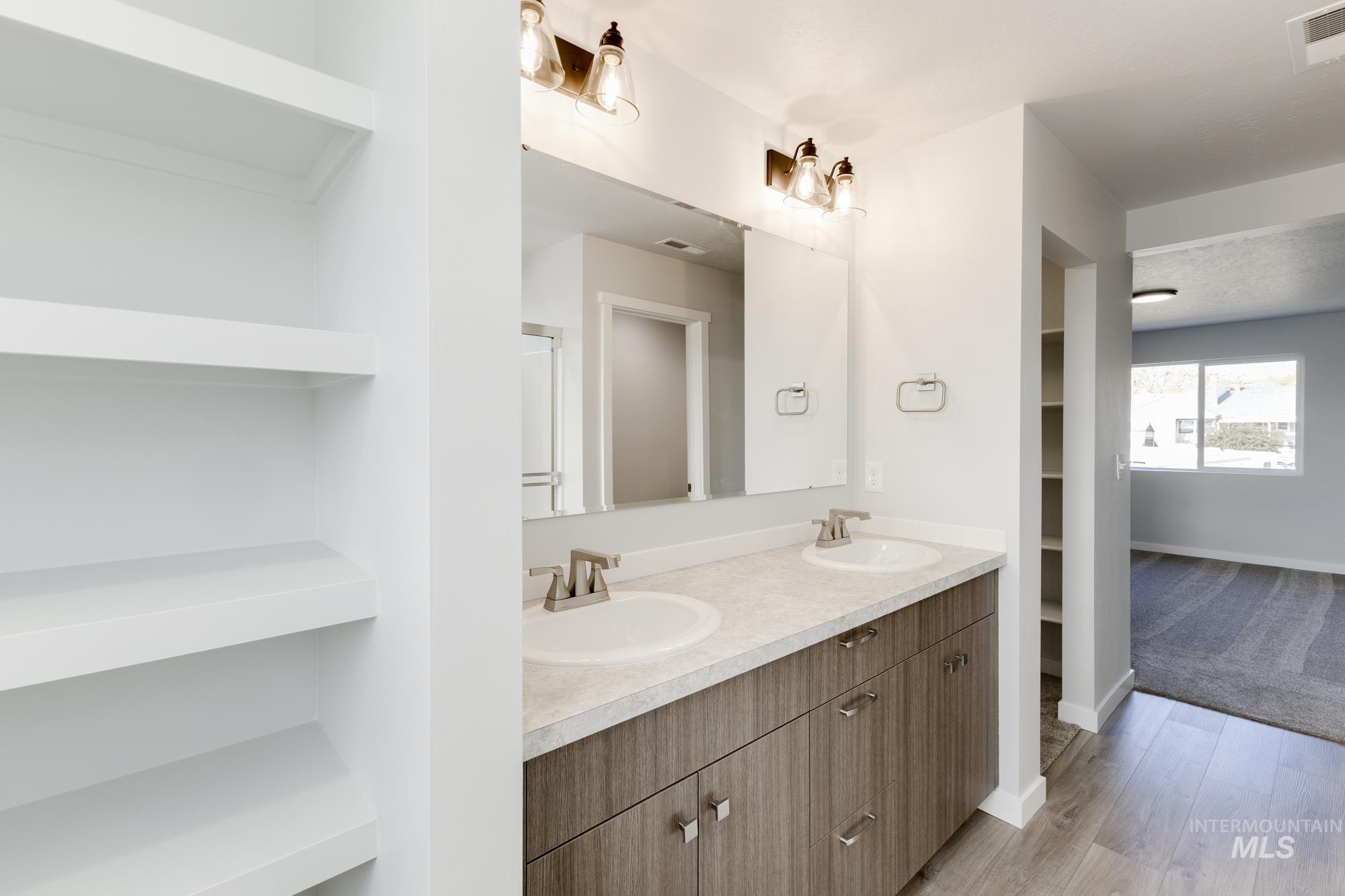 Bathroom featuring double vanity, a walk in closet, light wood-style floors, and built in features