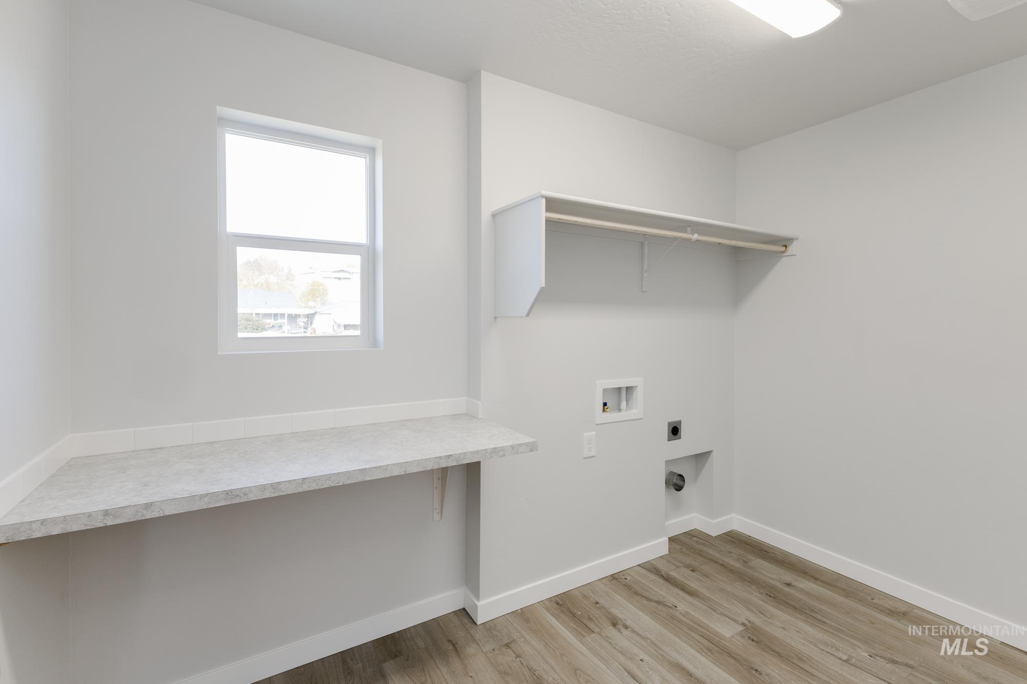 Laundry area with hookup for a washing machine, light wood-type flooring, and hookup for an electric dryer