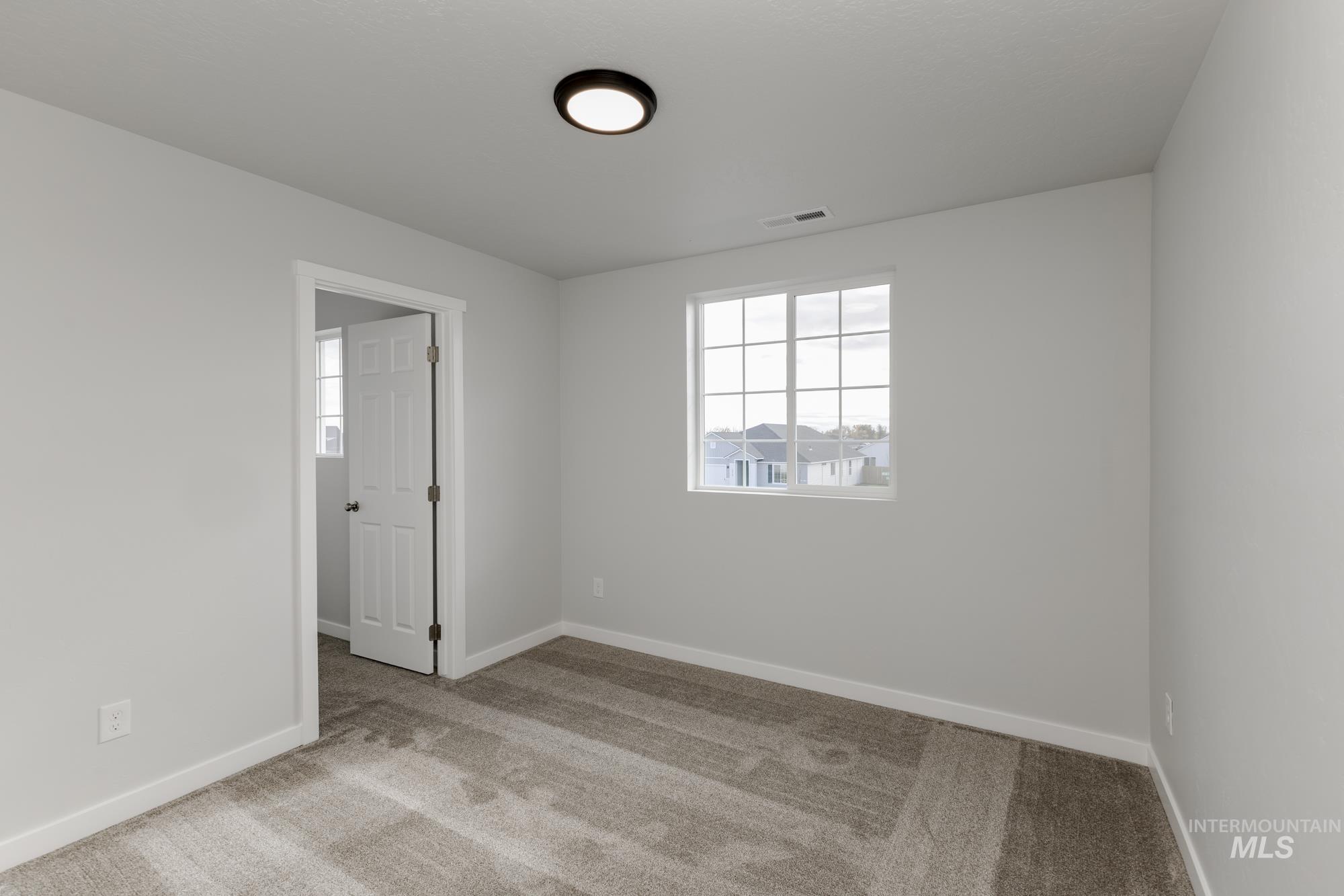Spare room with light carpet and baseboards