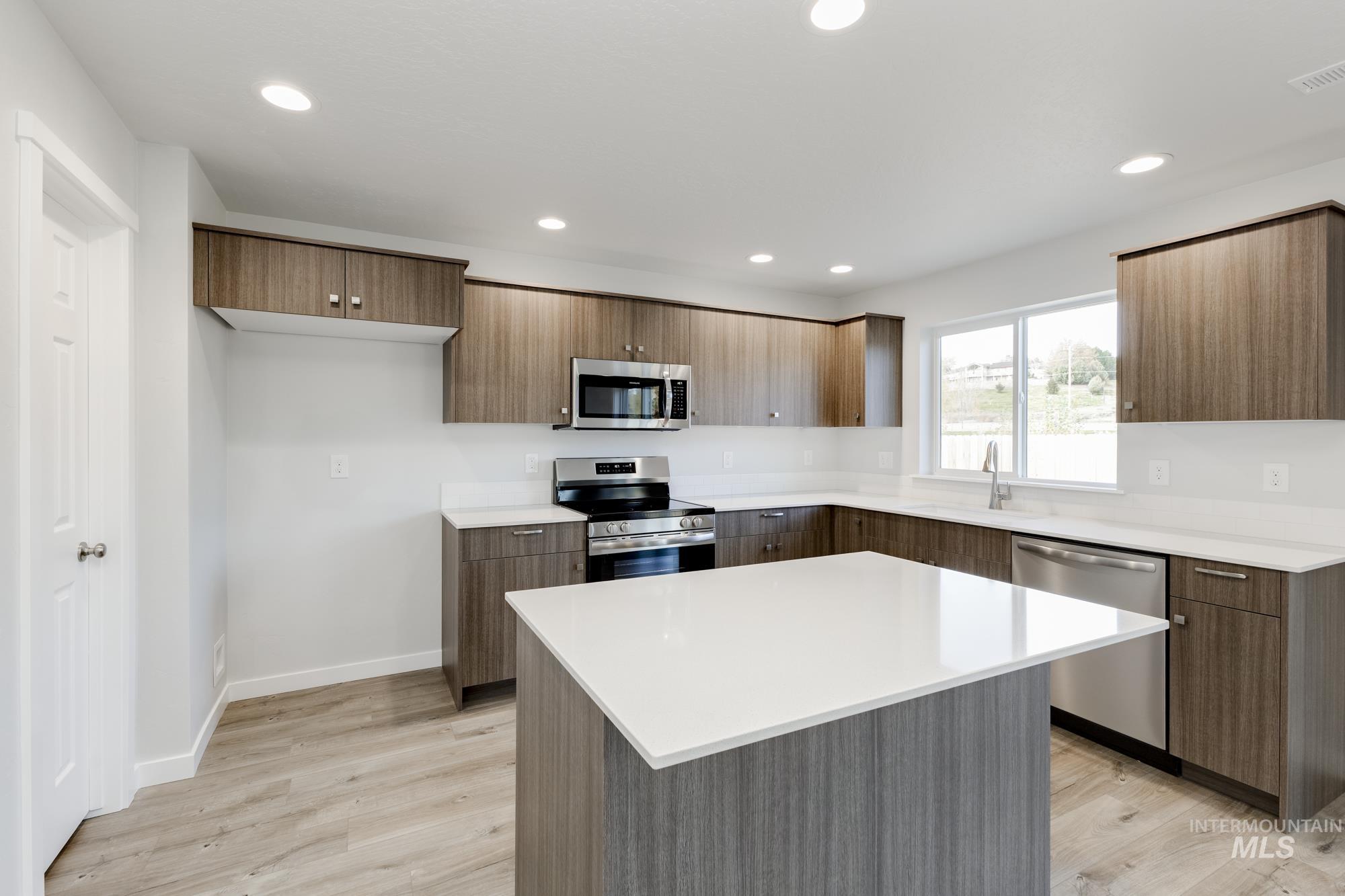 Kitchen featuring appliances with stainless steel finishes, a center island, light wood-style floors, modern cabinets, and recessed lighting