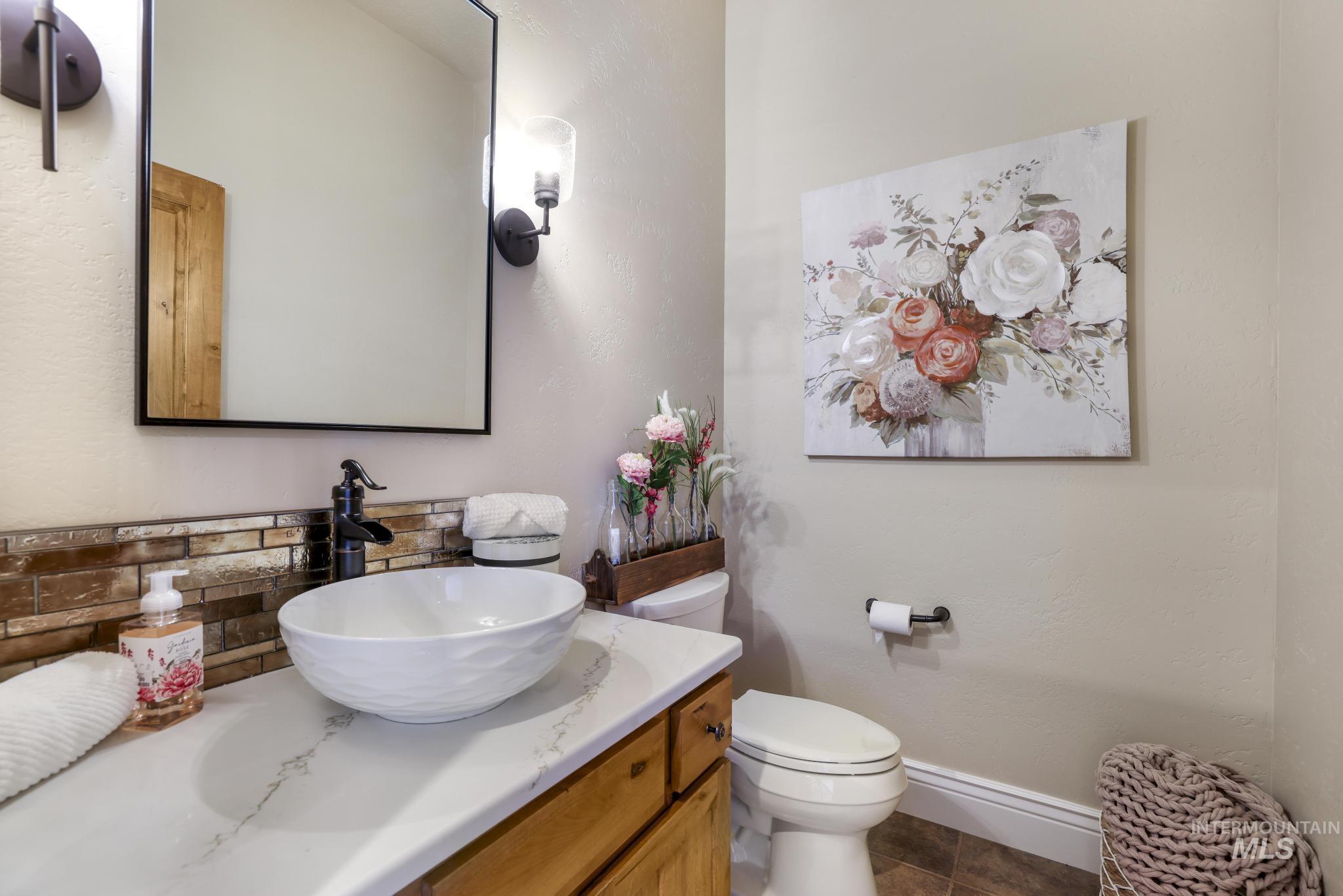 Bathroom featuring vanity, decorative backsplash, and dark tile patterned flooring