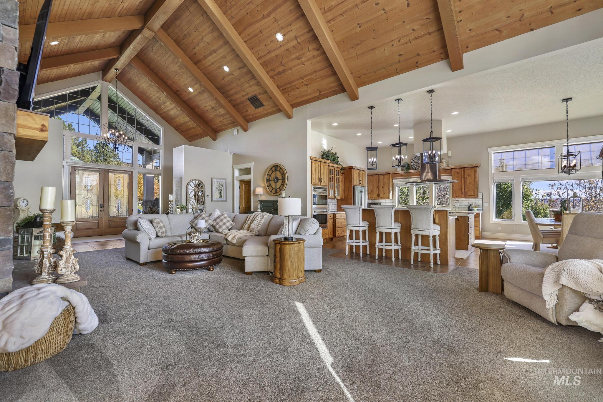 Living area with a chandelier, high vaulted ceiling, dark carpet, a wooden ceiling with exposed beams, and recessed lighting