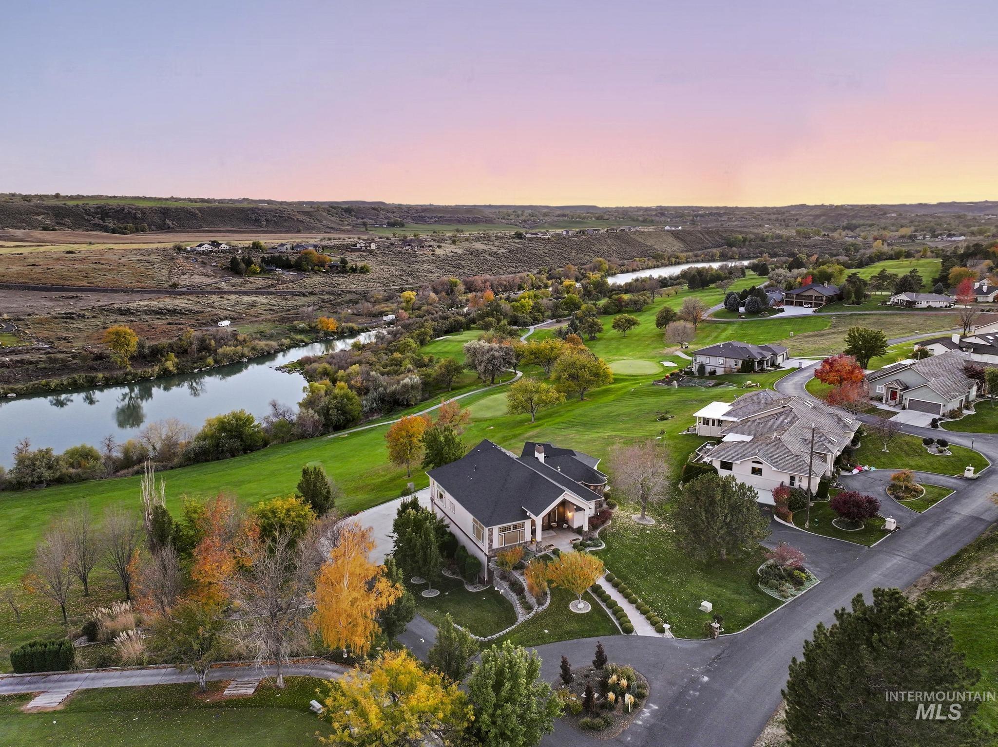 Aerial view at dusk of a water view, a residential view, and view of golf course