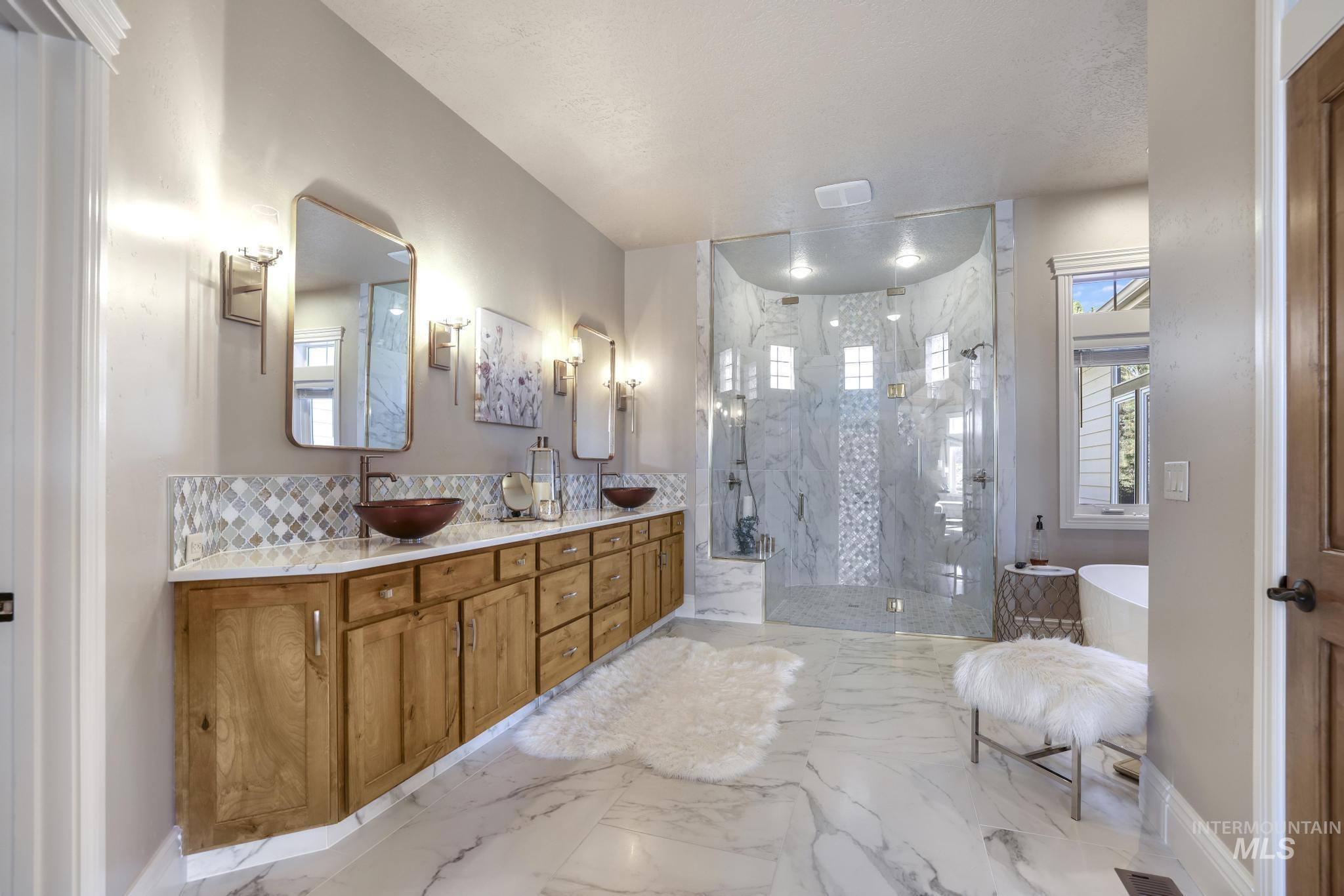 Bathroom featuring double vanity, a marble finish shower, light marble finish flooring, decorative backsplash, and a soaking tub