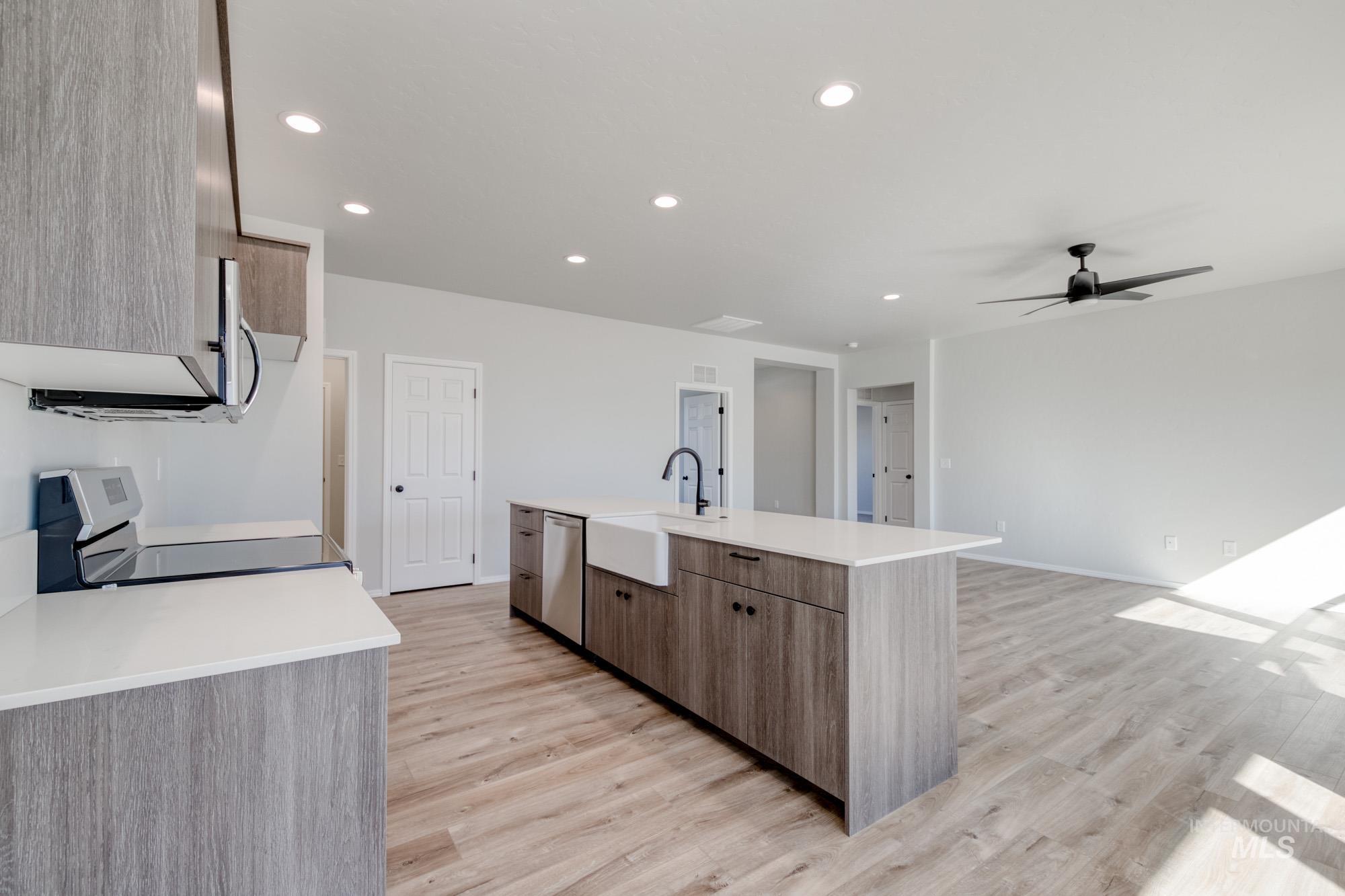Kitchen featuring light wood-style flooring, recessed lighting, appliances with stainless steel finishes, an island with sink, and ceiling fan