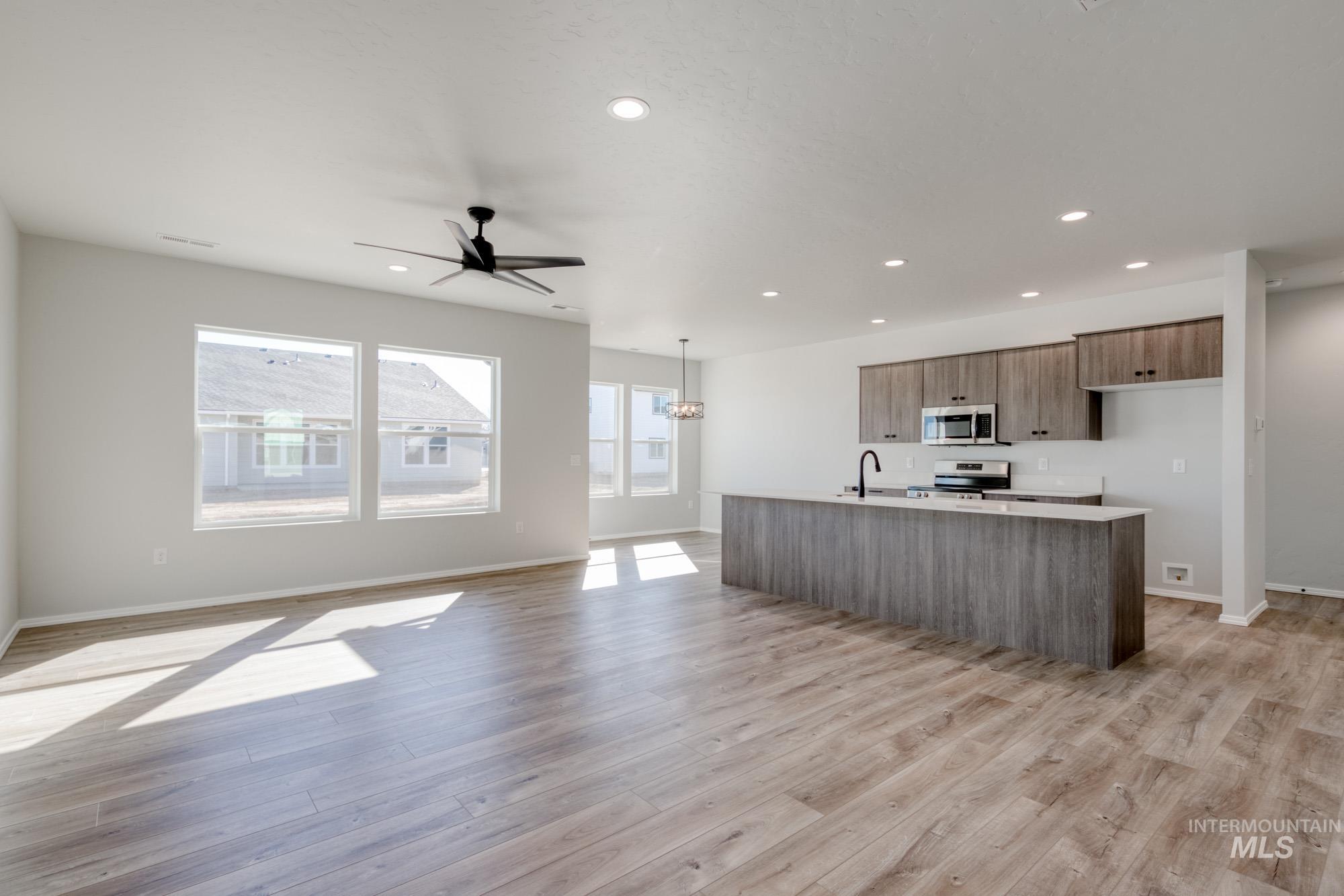 Kitchen featuring open floor plan, modern cabinets, recessed lighting, an island with sink, and ceiling fan