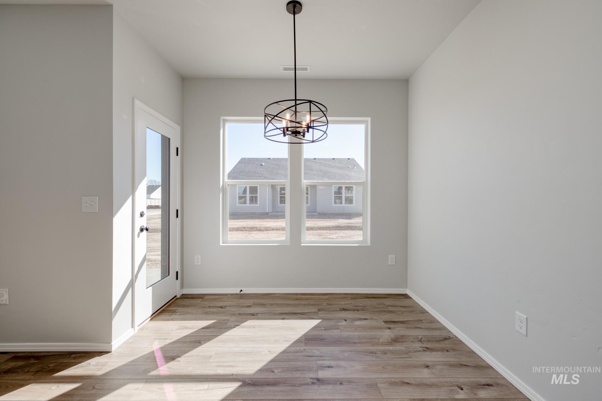 Unfurnished dining area with a chandelier and light wood-type flooring