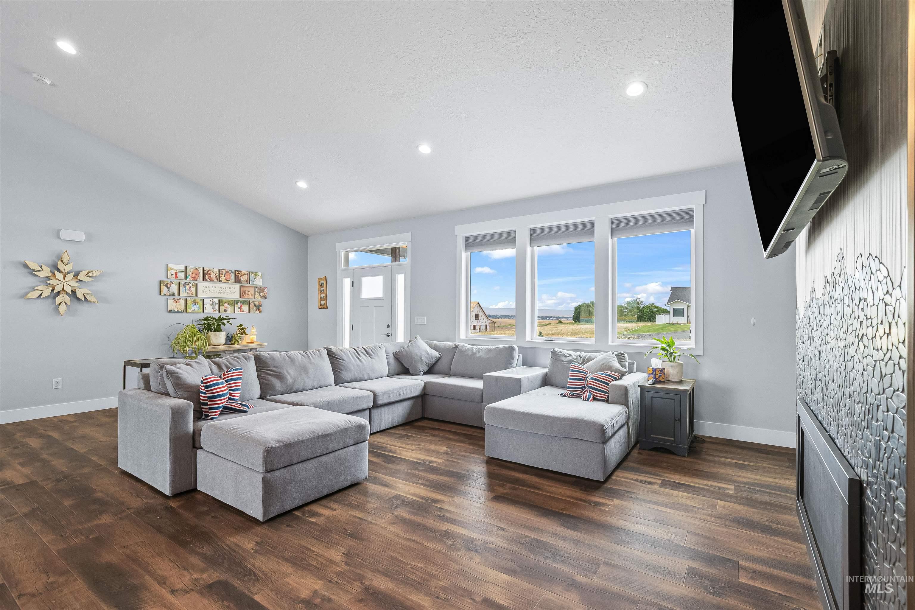 Living room with dark wood-style flooring, a fireplace, vaulted ceiling, and recessed lighting