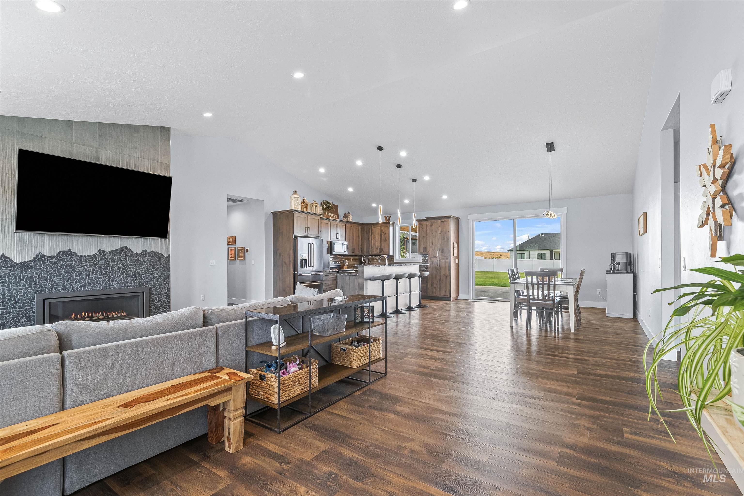 Living area with vaulted ceiling, recessed lighting, a tile fireplace, and dark wood finished floors
