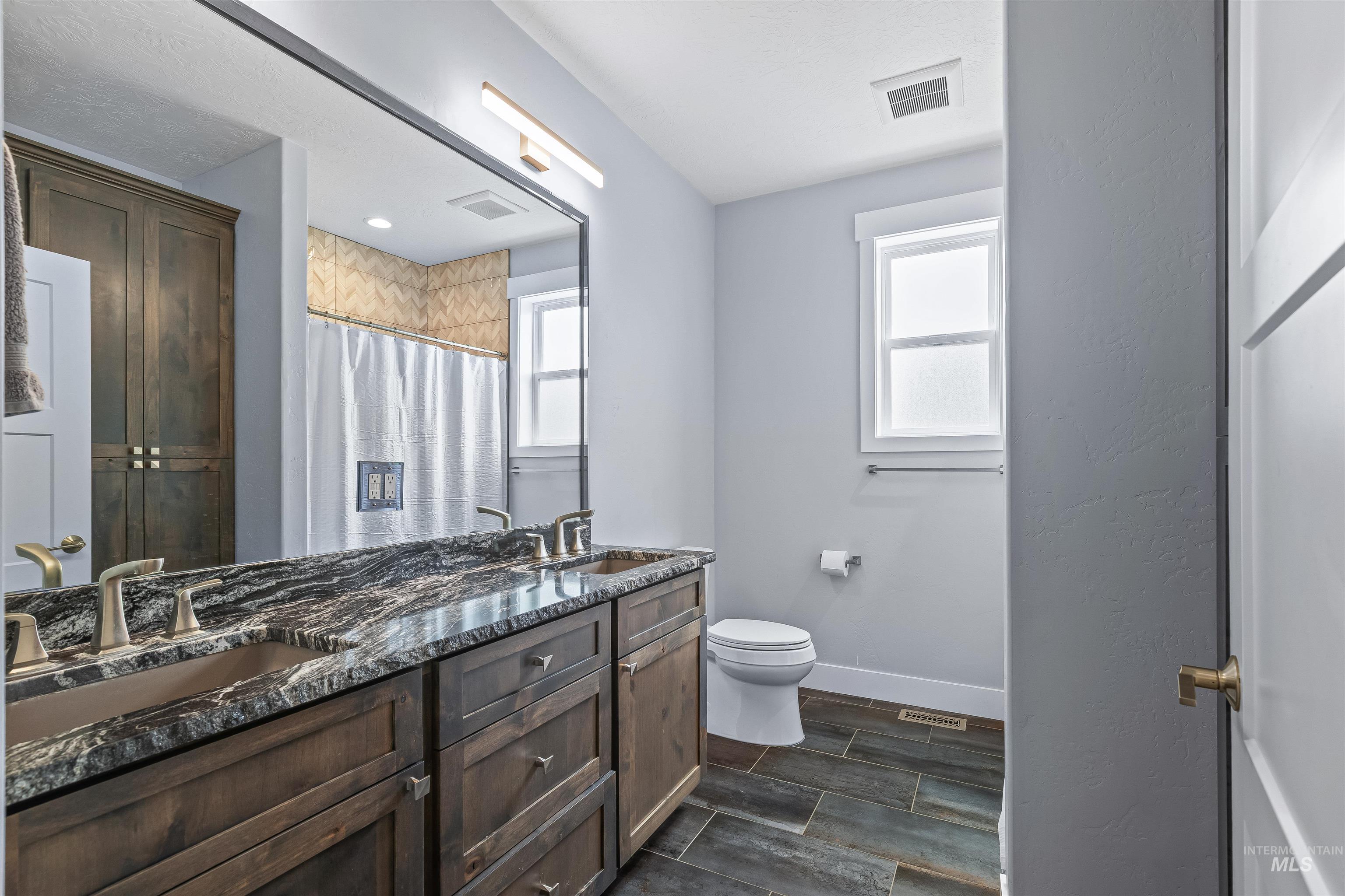 Full bath with wood finish floors, double vanity, and curtained shower