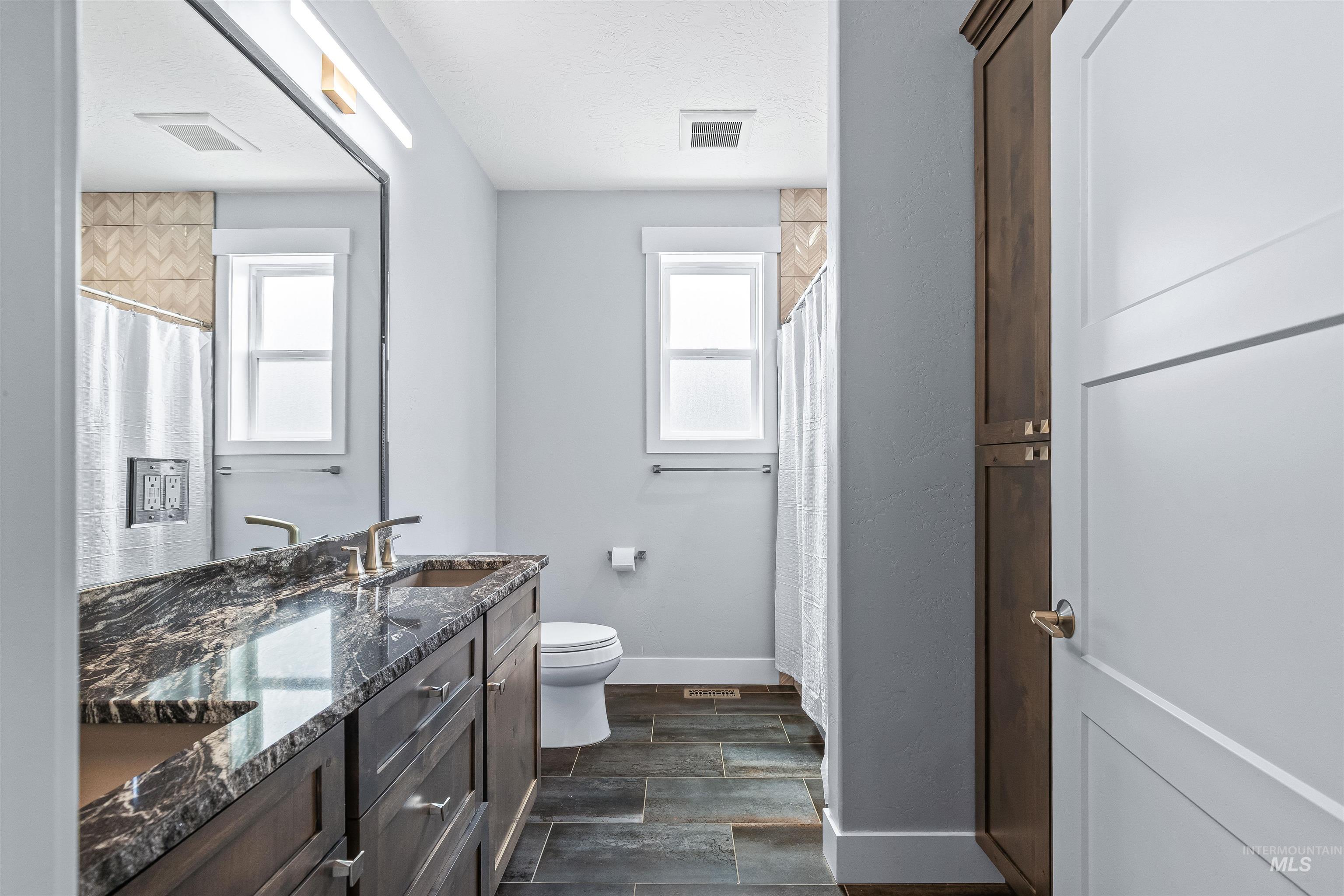 Full bath with double vanity and a shower with shower curtain