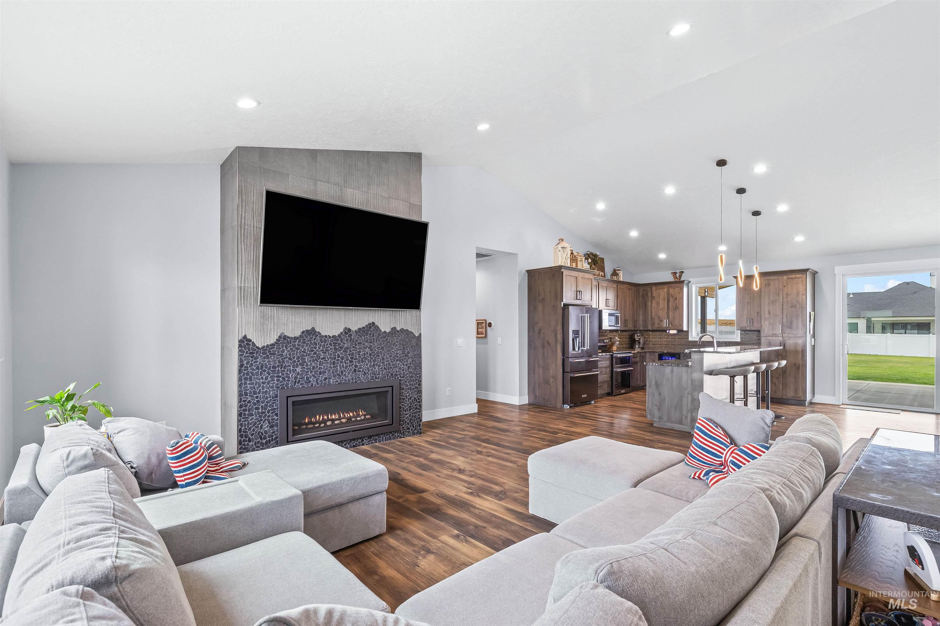 Living area featuring dark wood finished floors, a tile fireplace, recessed lighting, and lofted ceiling