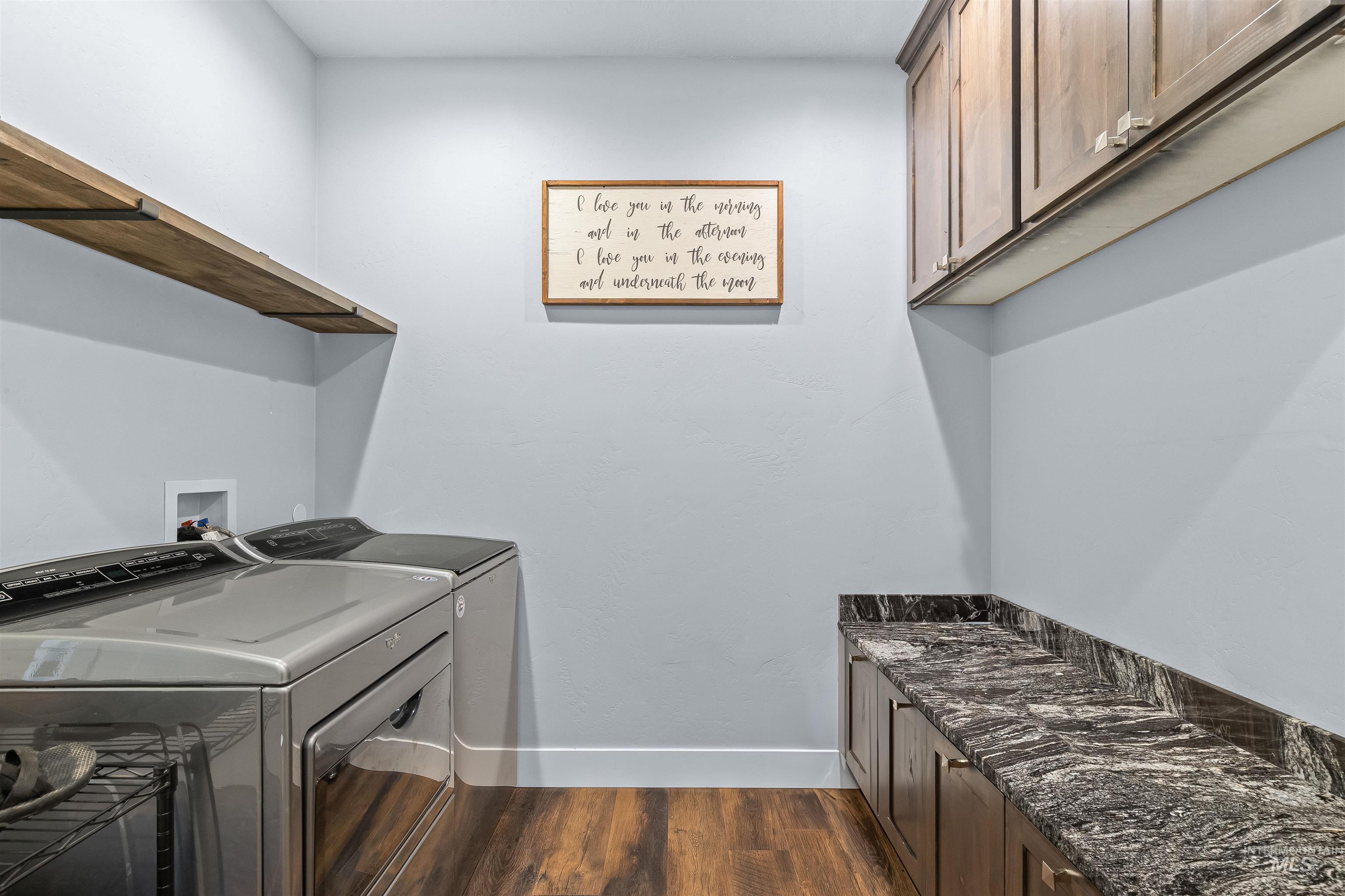 Washroom with dark wood-style flooring, separate washer and dryer, and cabinet space
