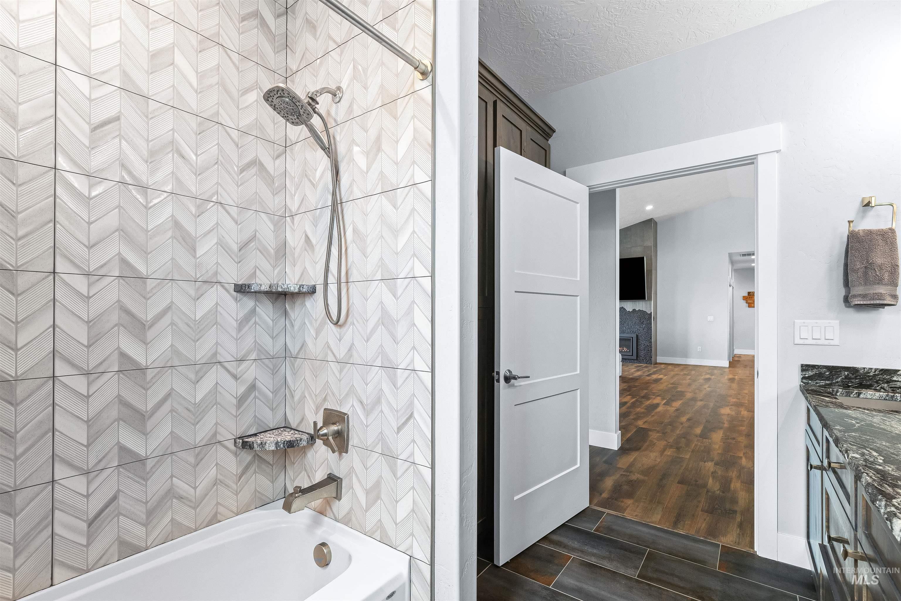 Full bathroom with shower / tub combination, a textured ceiling, wood finished floors, and vanity