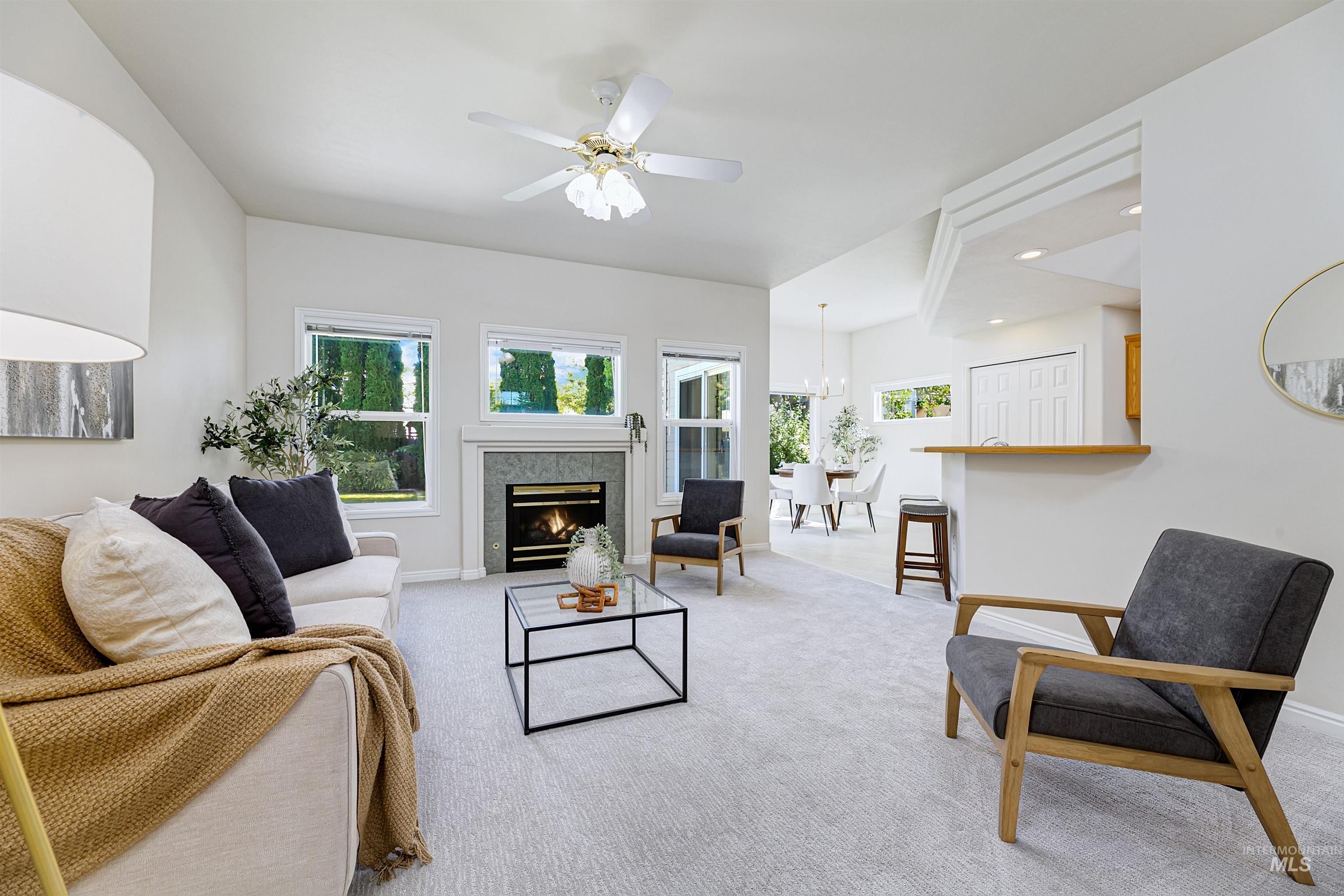 Living room featuring light colored carpet, plenty of natural light, a ceiling fan, and a tile fireplace