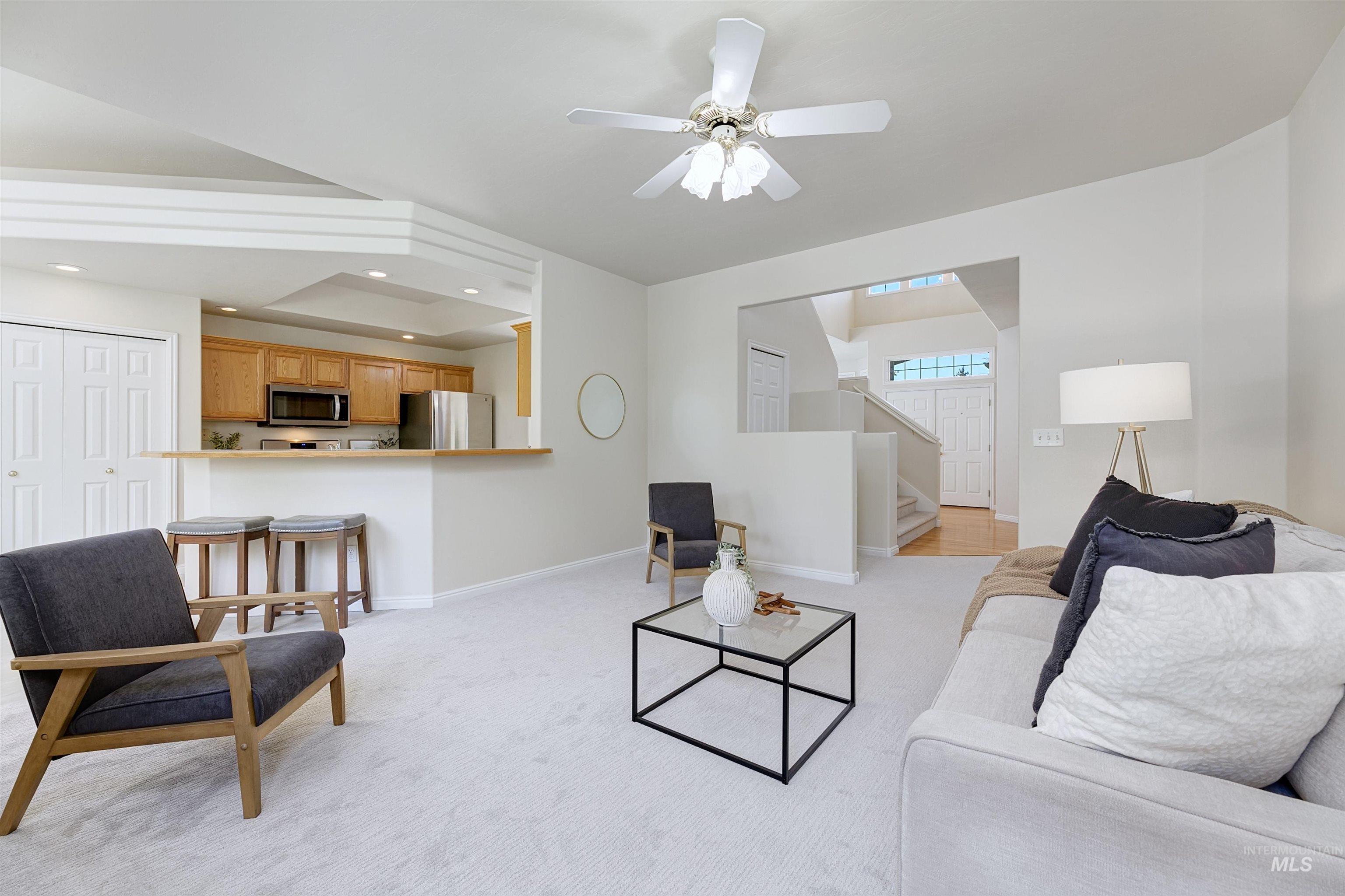 Living area with recessed lighting, ceiling fan, light colored carpet, and stairway