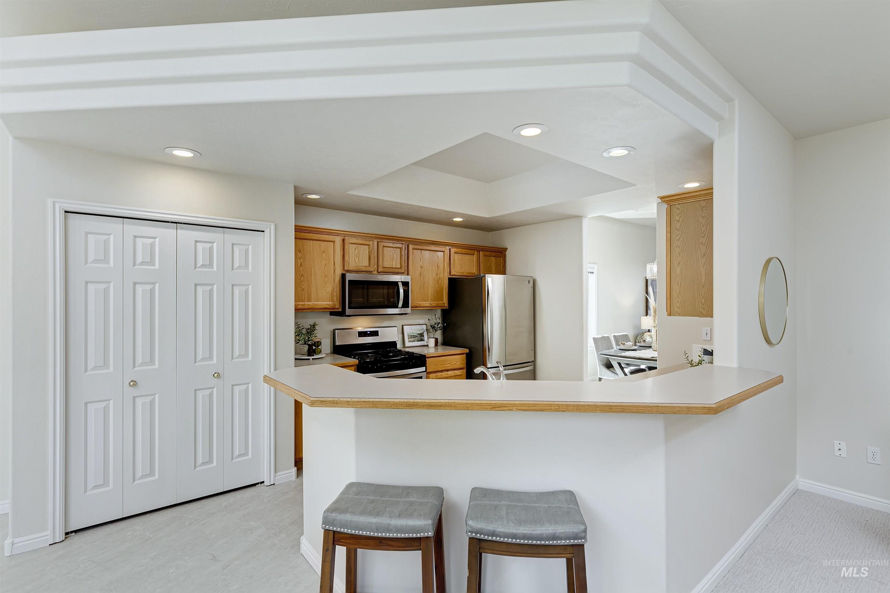 Kitchen featuring light countertops, a kitchen bar, recessed lighting, stainless steel appliances, and a peninsula