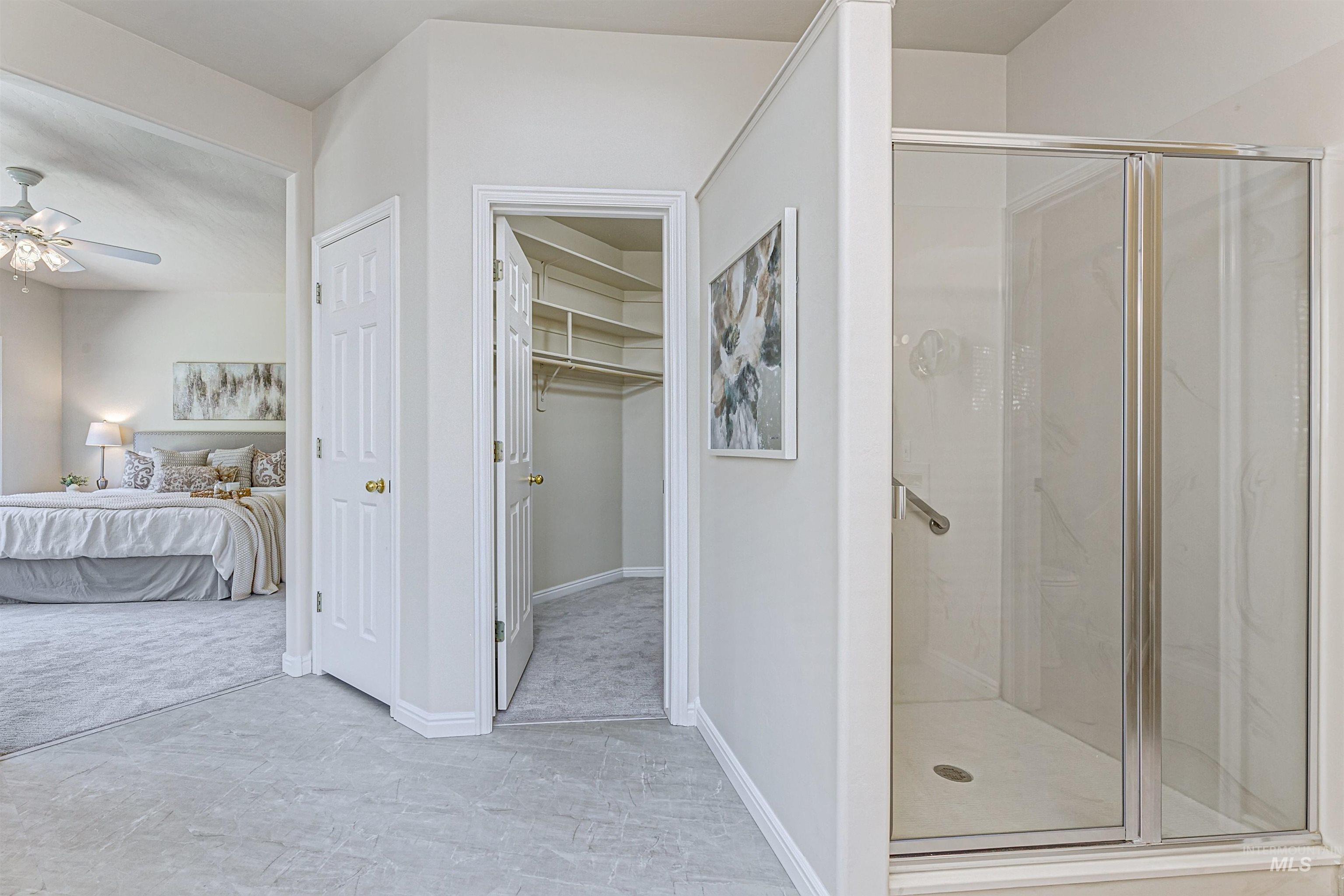 Ensuite bathroom with a stall shower, a walk in closet, and ceiling fan