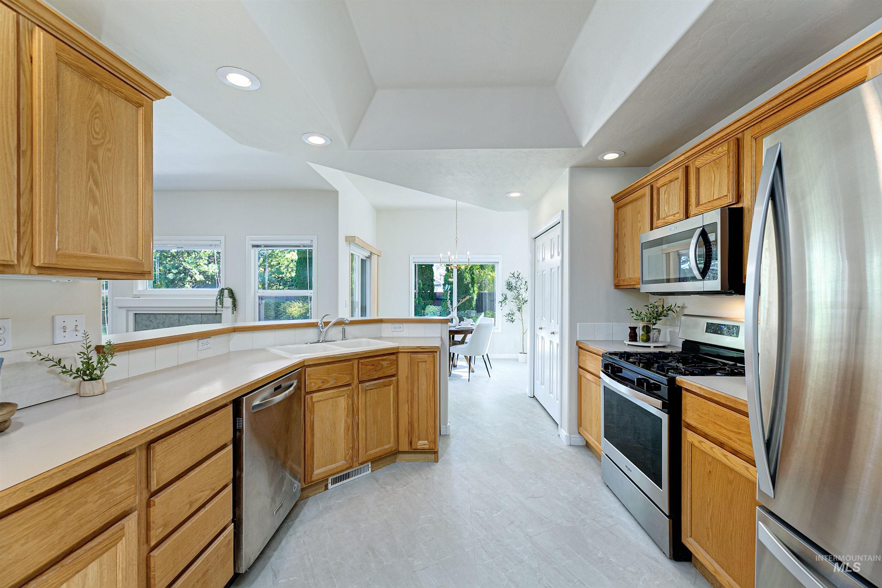 Kitchen with appliances with stainless steel finishes, recessed lighting, light countertops, a chandelier, and a peninsula