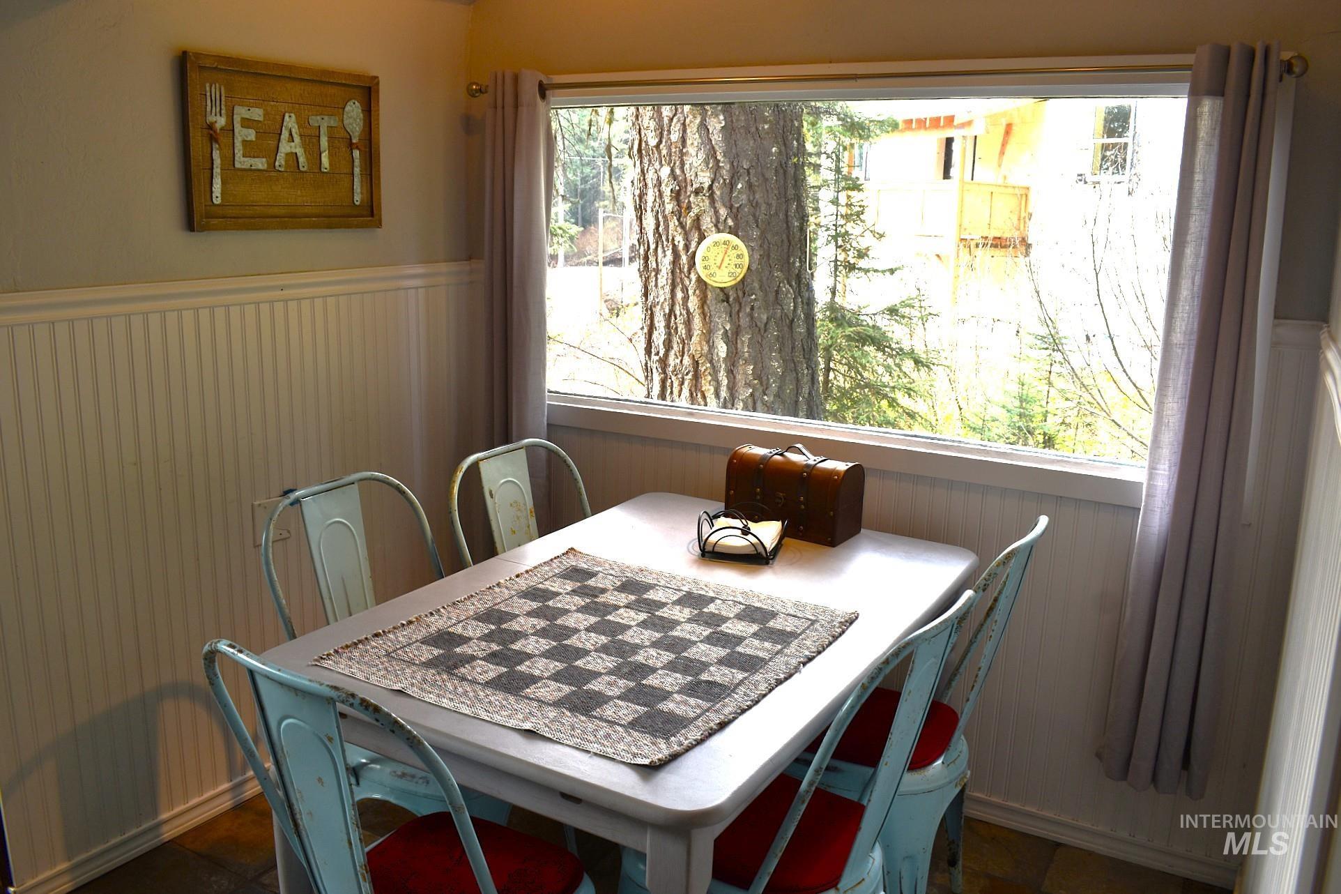 Dining area with beadboard wainscoting, framed window, and drapes
