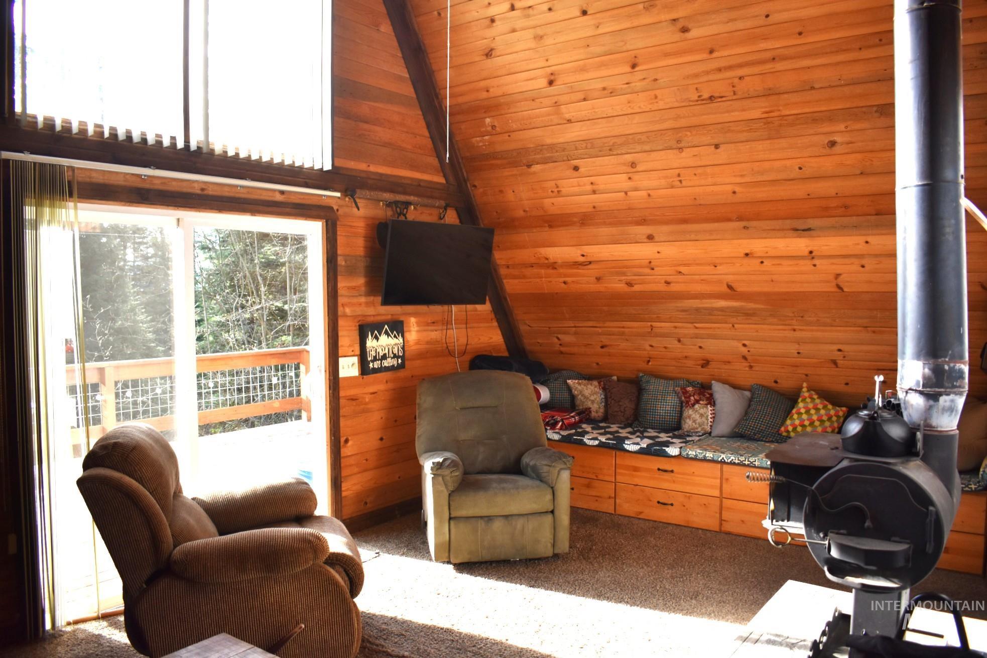 Inviting living space featuring wood-finish wall paneling, a built-in wood-burning stove, and a wall-mounted television
