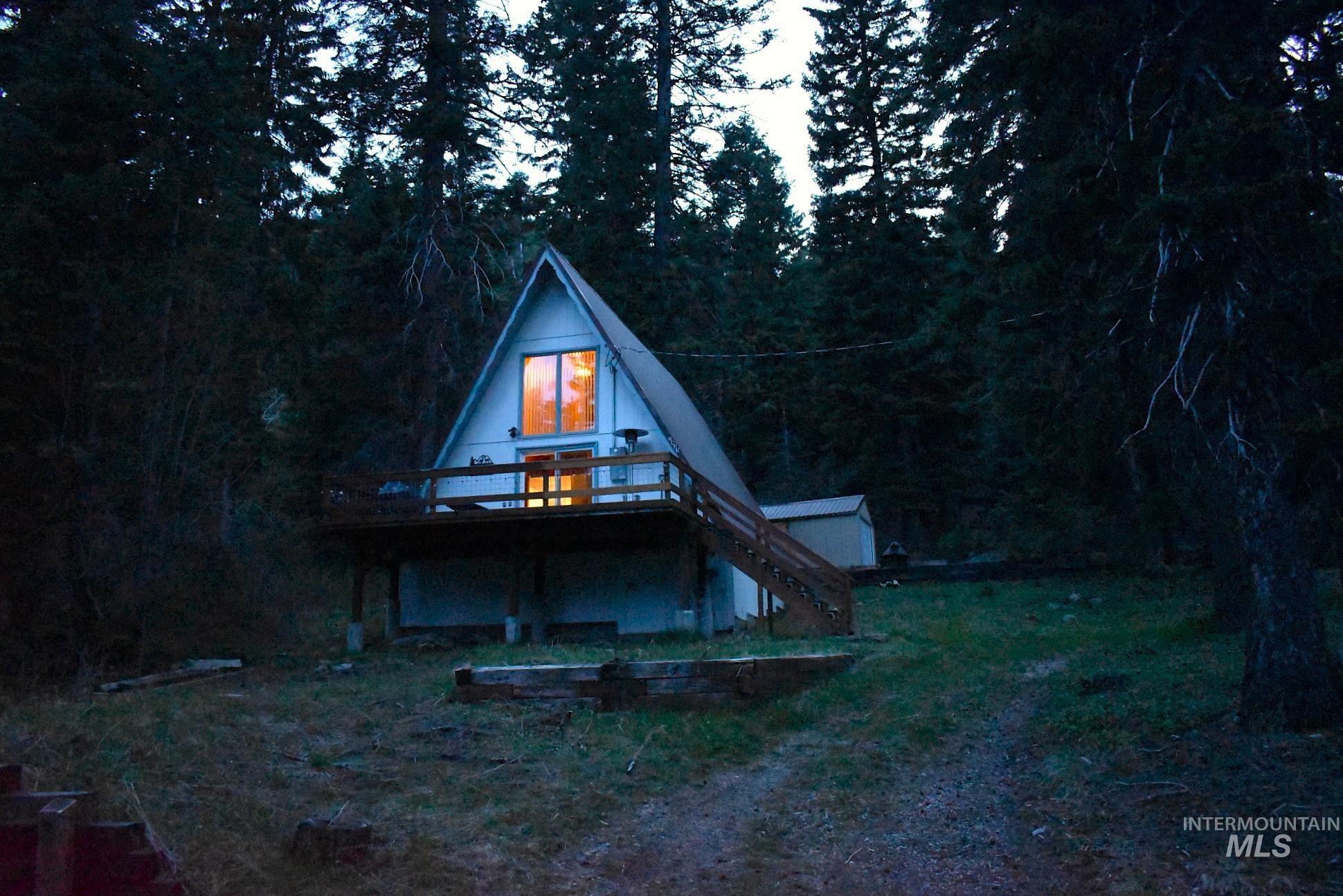 A-frame property featuring a raised wooden deck with railings, exterior staircase, and a shed