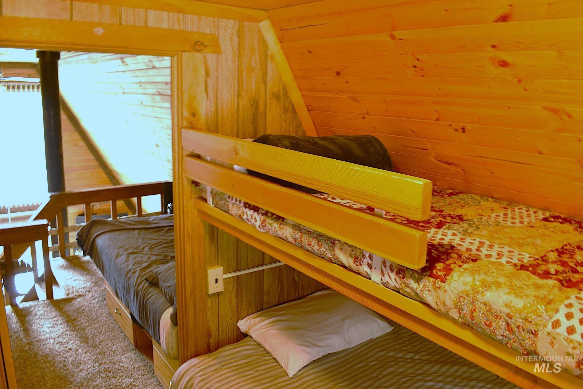 Wood-paneled interior featuring a built-in bunk bed system with integrated power outlet, an additional built-in bed with under-bed storage drawers, and a wooden railing