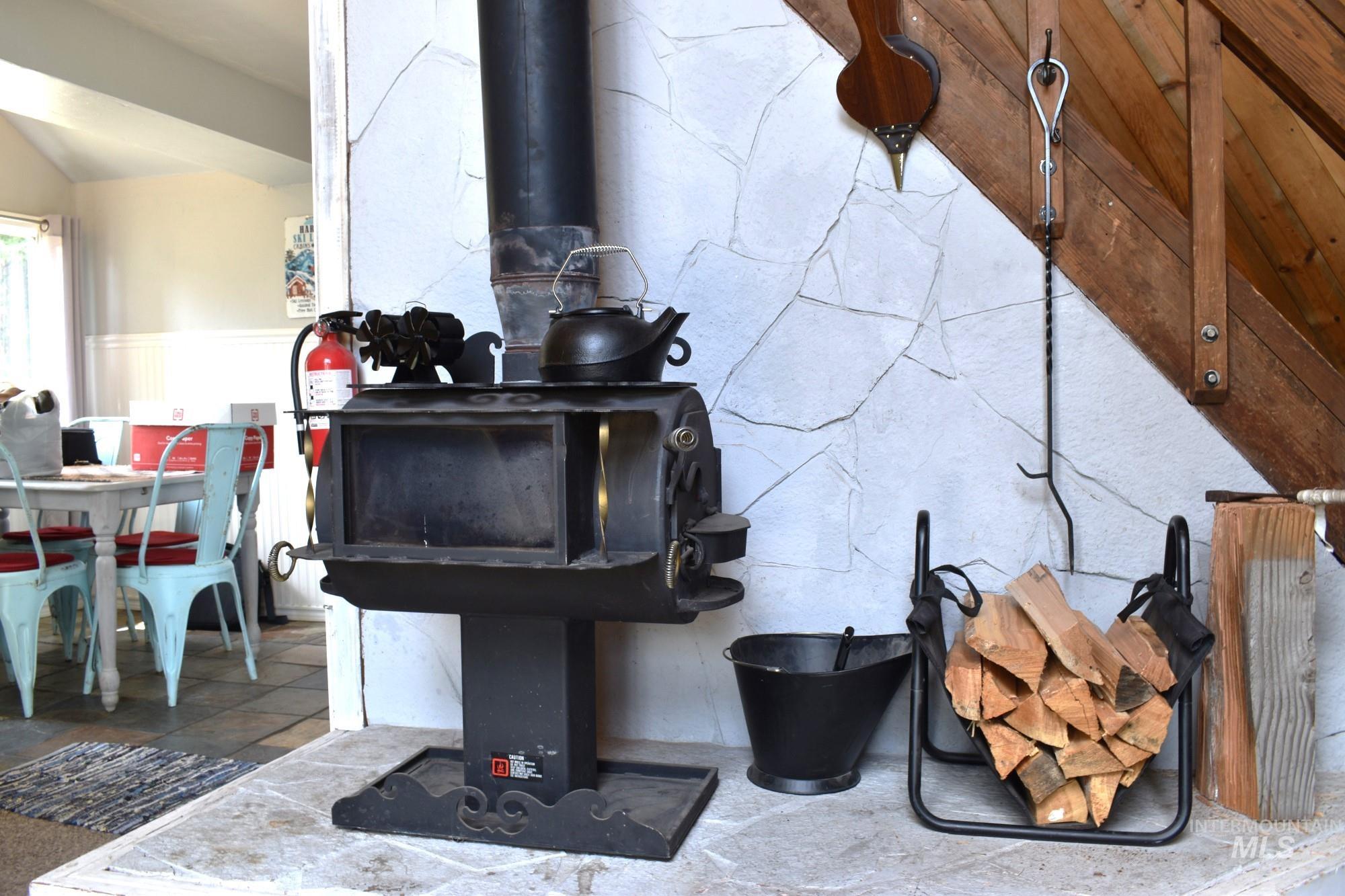 Freestanding black wood-burning stove with a stone-clad surround and a wood staircase