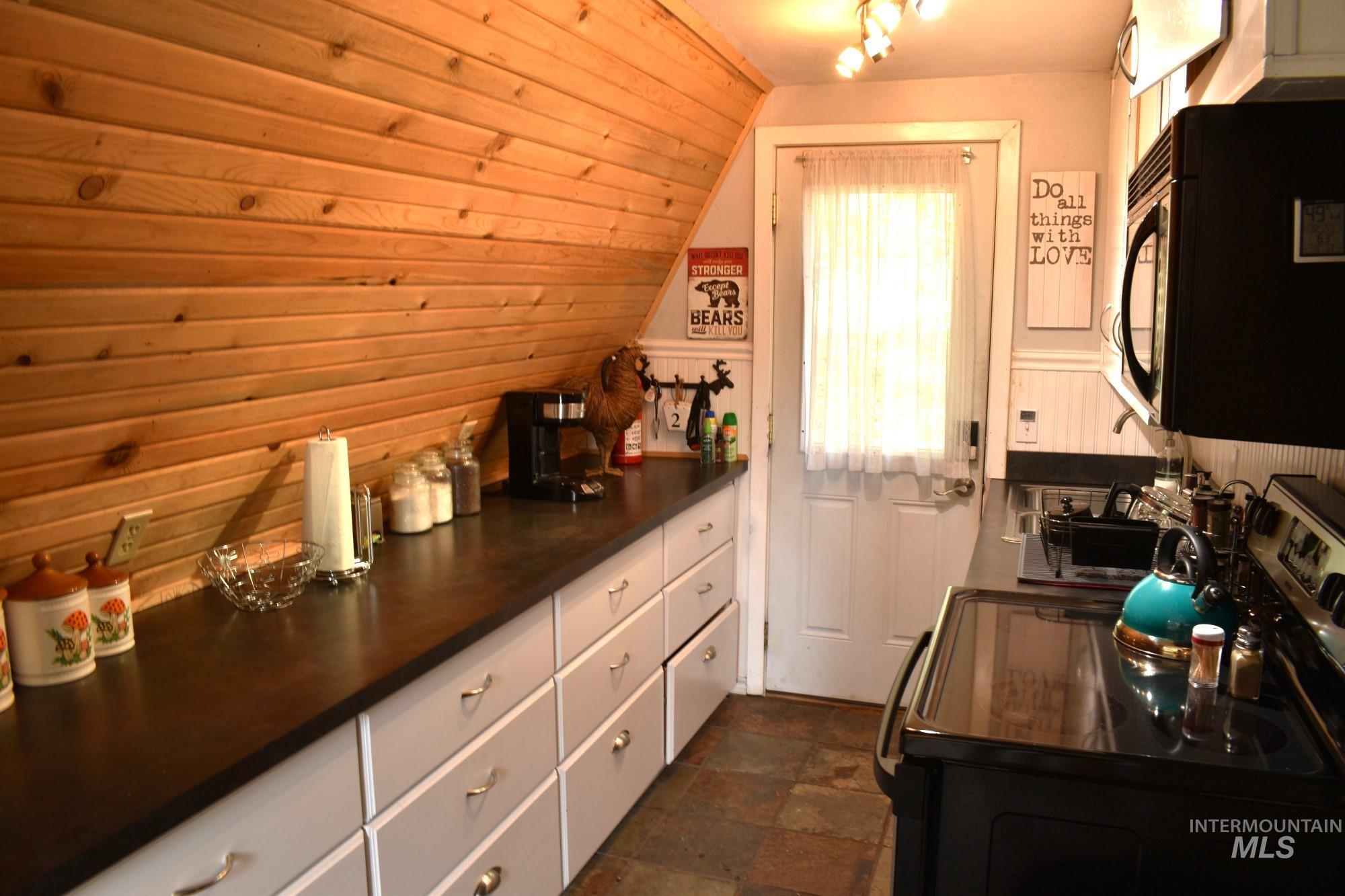 Compact kitchen featuring wood-paneled walls and a slate-style flooring