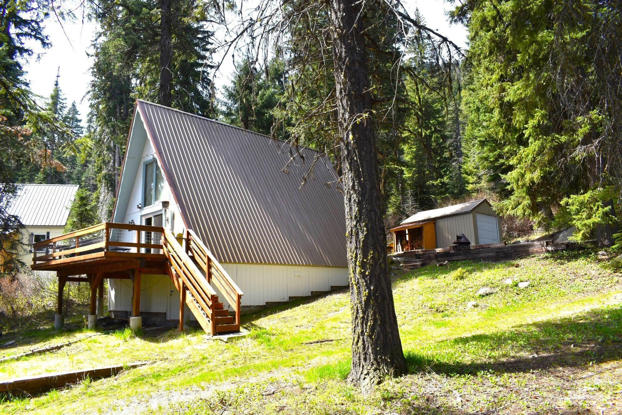 A-frame style residence with a corrugated metal roof, elevated wood deck, and wood stairs