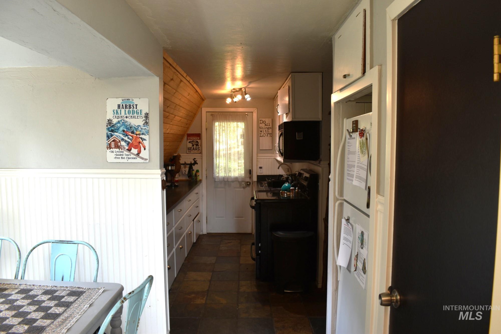 Galley kitchen featuring dark-toned flooring, white upper and lower cabinetry, and dark countertops