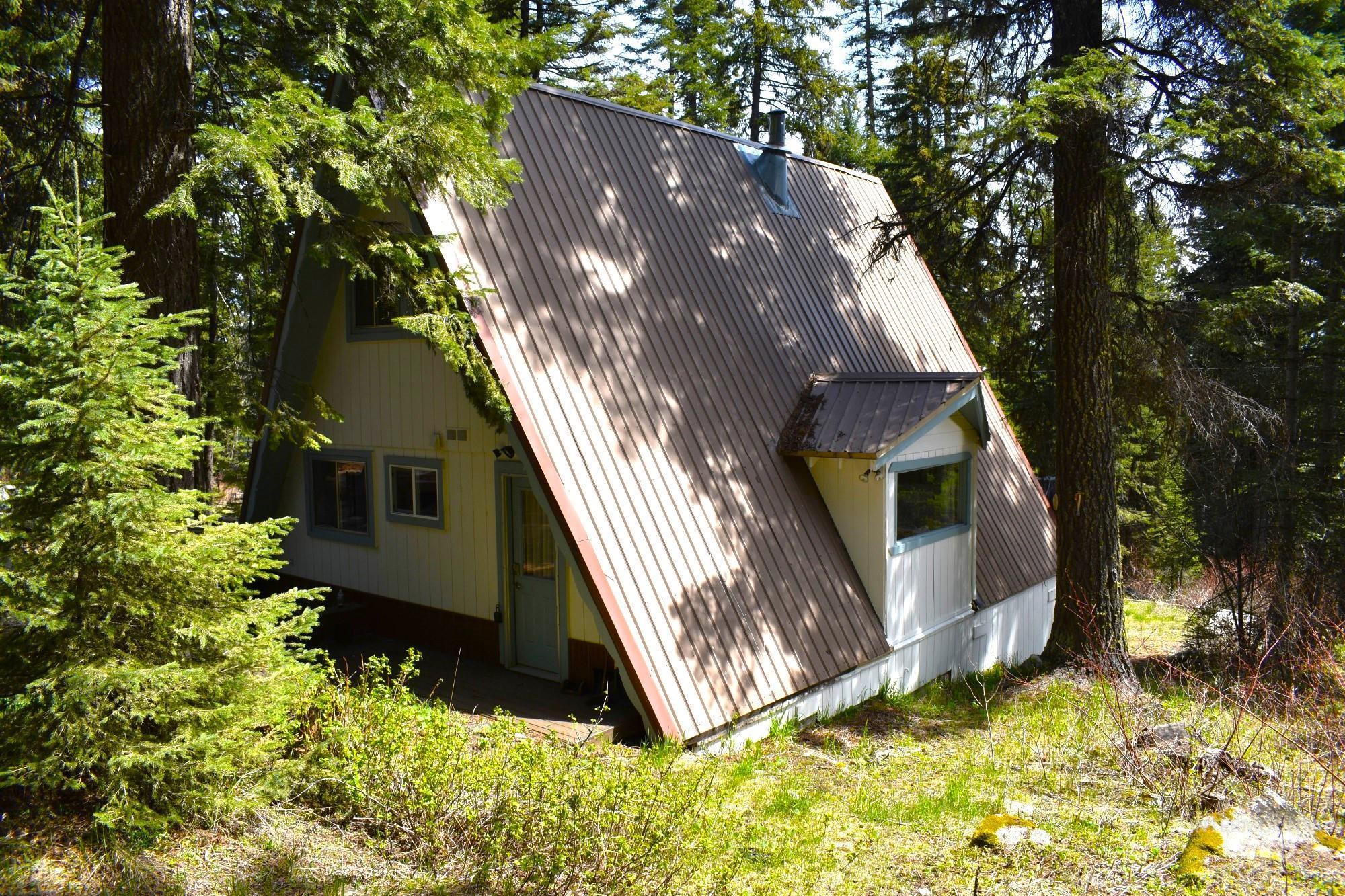 A-frame structure featuring light-colored siding and a corrugated metal roof
