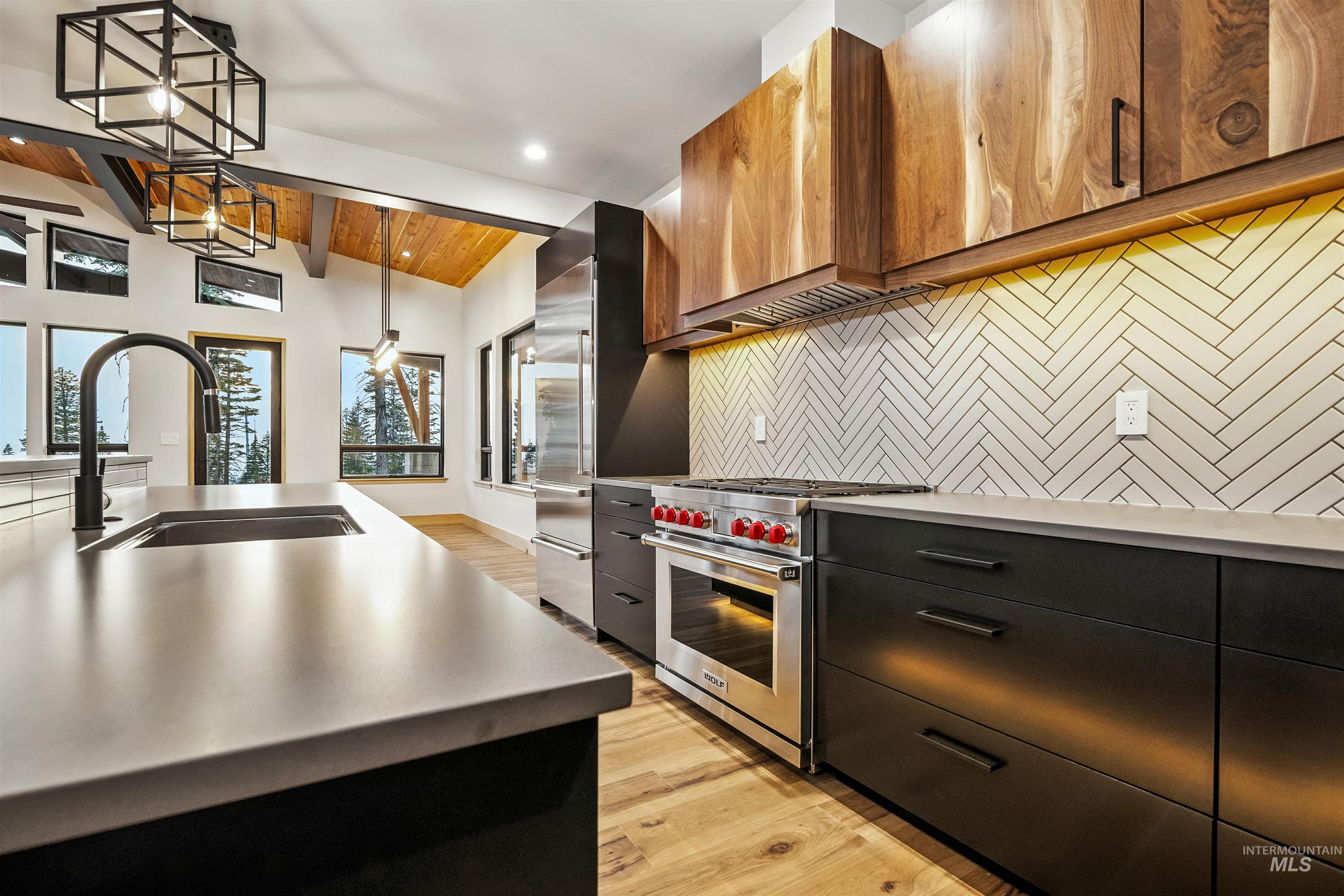 Kitchen featuring pendant lighting, backsplash, high end appliances, light wood-style floors, and wood ceiling