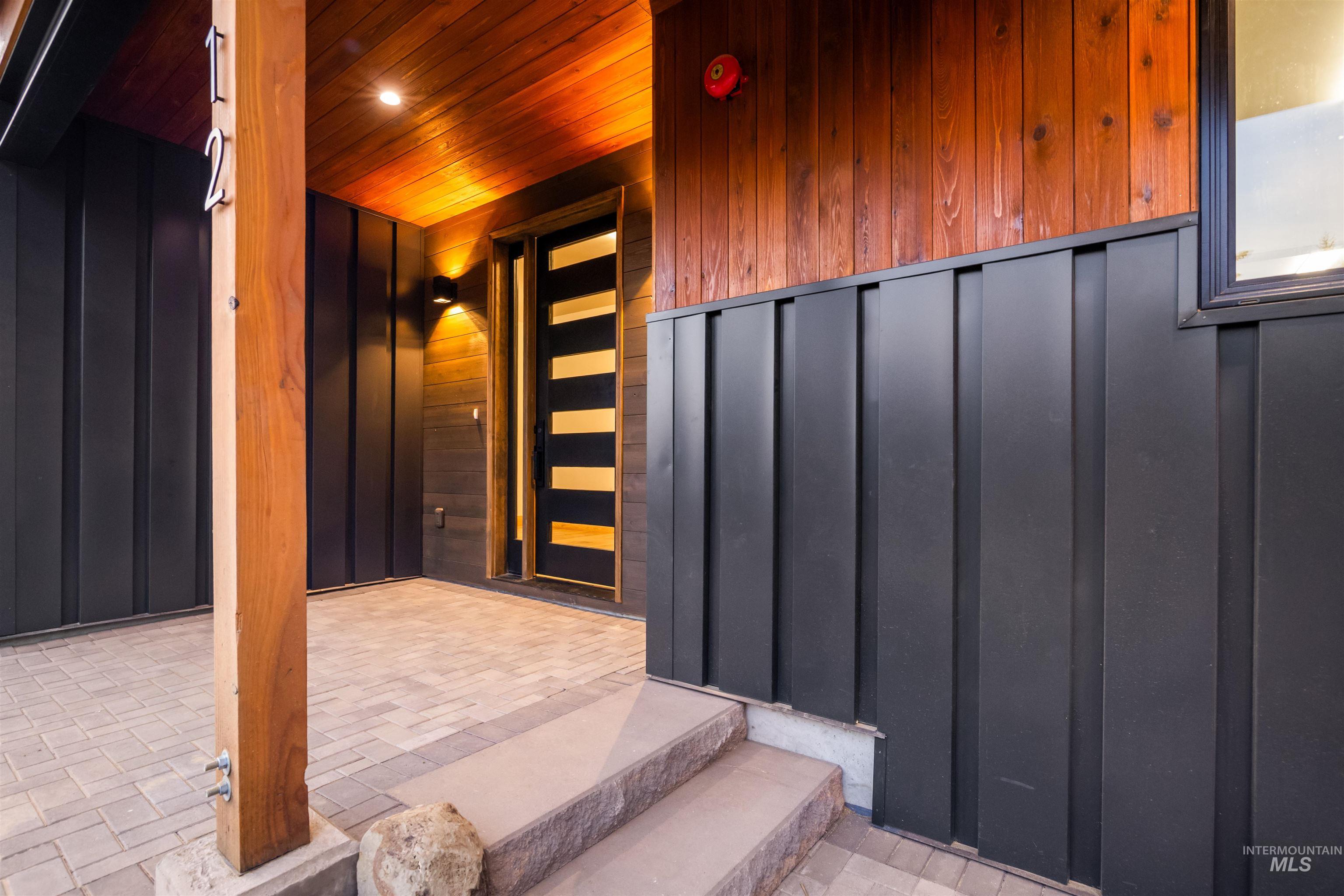 Property entrance with board and batten siding and a patio area