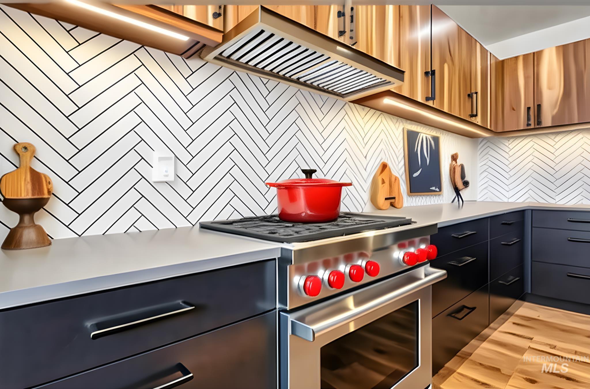 Kitchen with luxury stove, tasteful backsplash, wall chimney range hood, light wood-style floors, and light stone counters