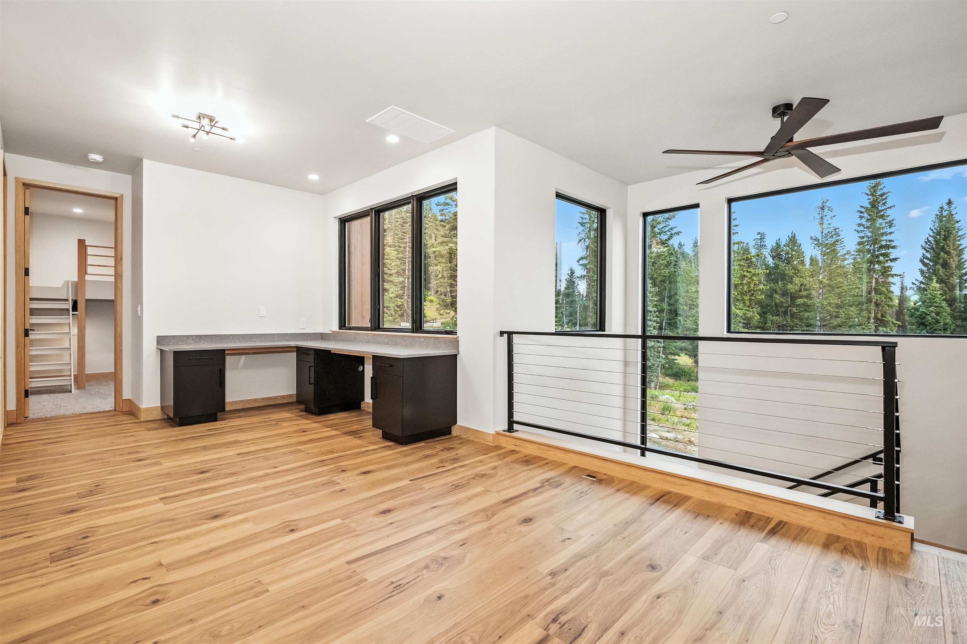 Unfurnished office featuring light wood-style flooring, built in desk, recessed lighting, and ceiling fan