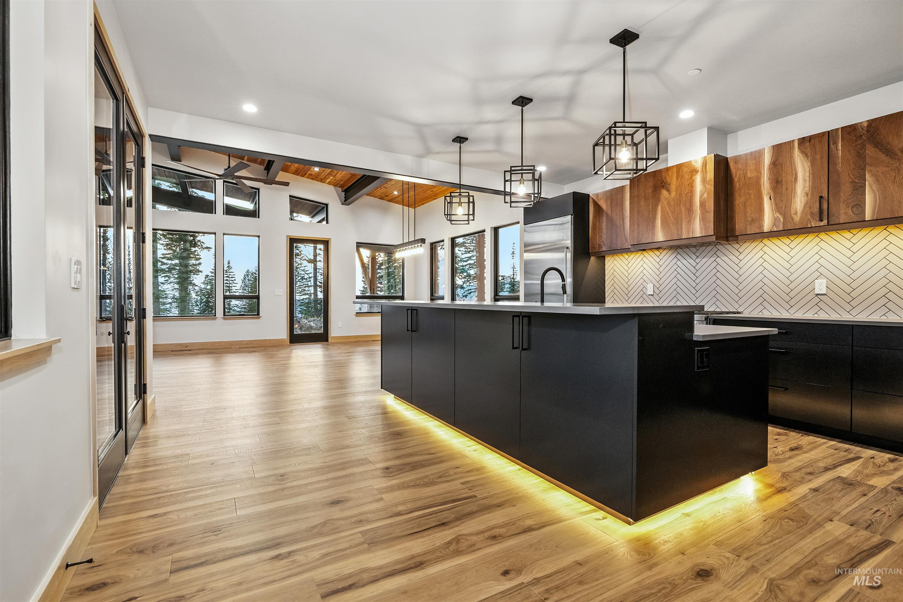 Kitchen featuring tasteful backsplash, a kitchen island with sink, dark cabinetry, and modern cabinets