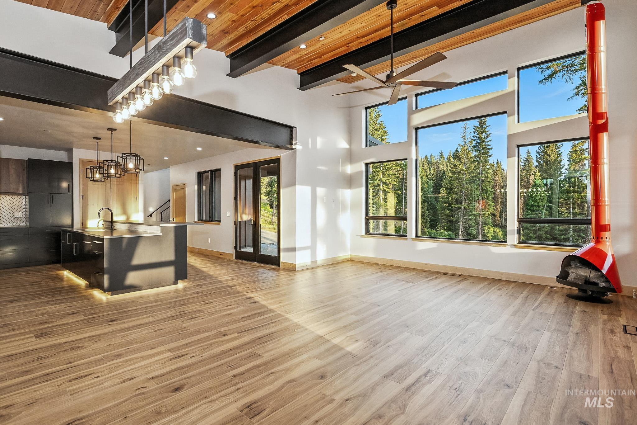 Unfurnished living room with beamed ceiling, light wood-style floors, a ceiling fan, recessed lighting, and a chandelier