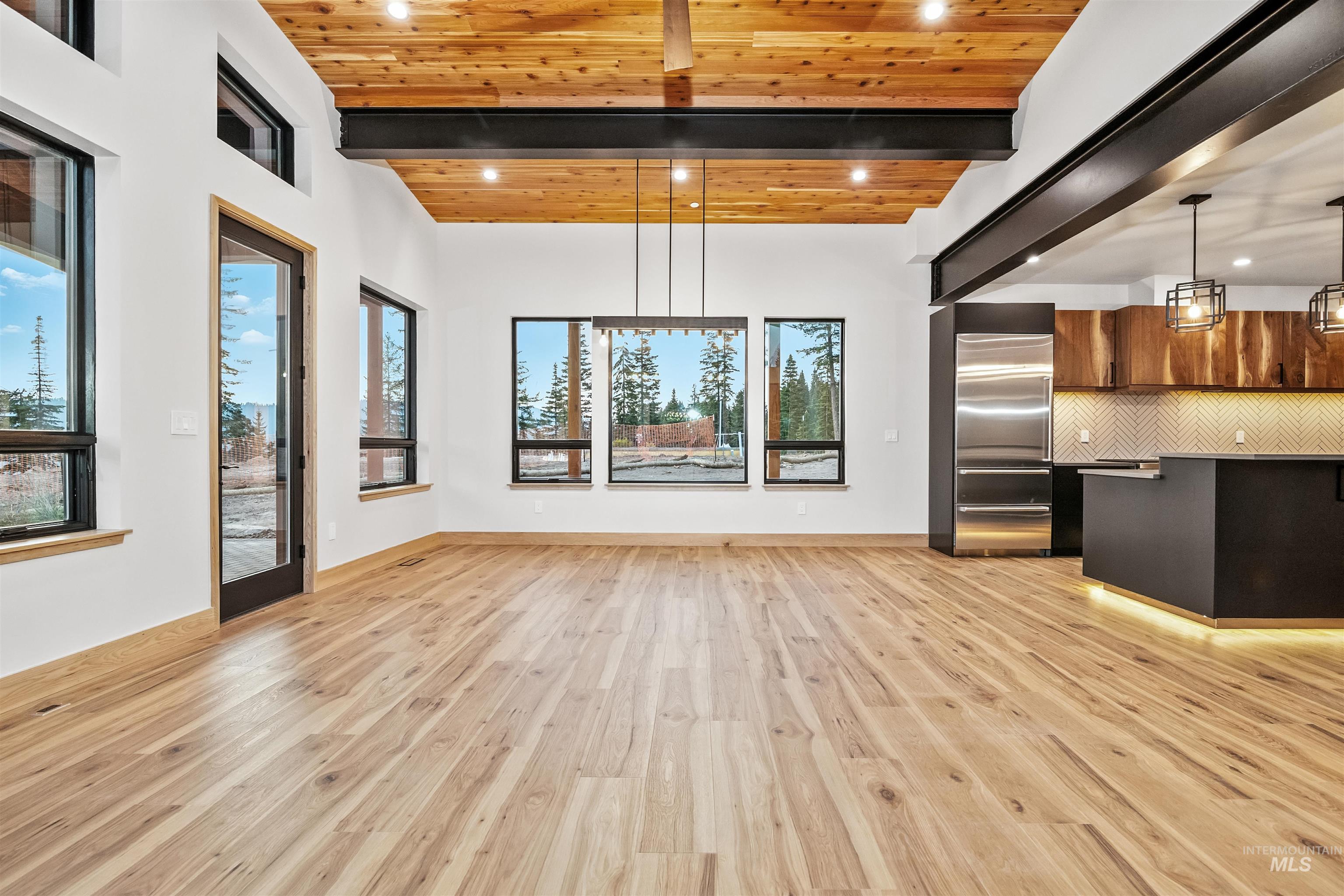 Unfurnished dining area with light wood finished floors, recessed lighting, and a wooden ceiling with exposed beams