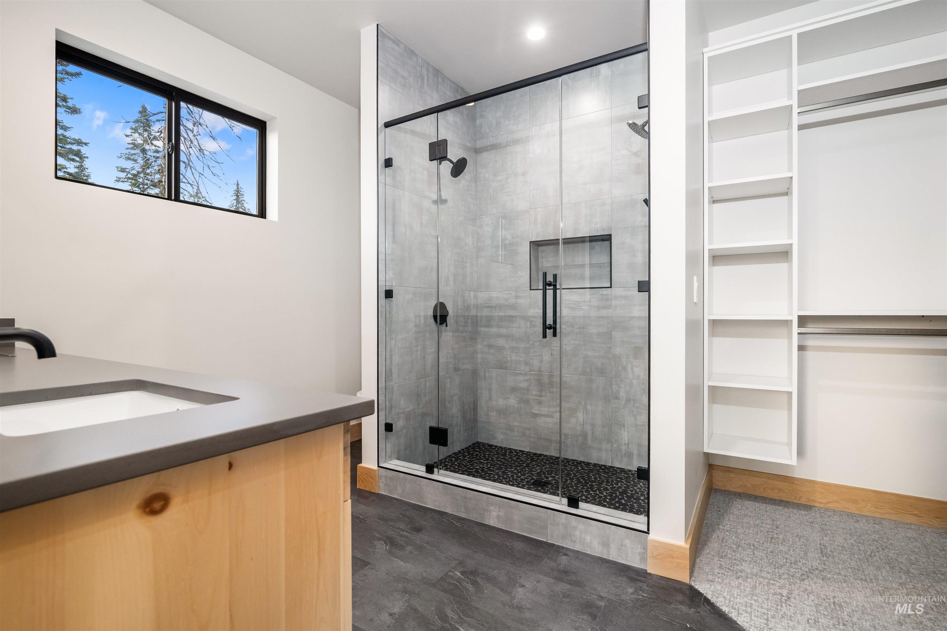 Bathroom featuring vanity, a shower stall, and a spacious closet