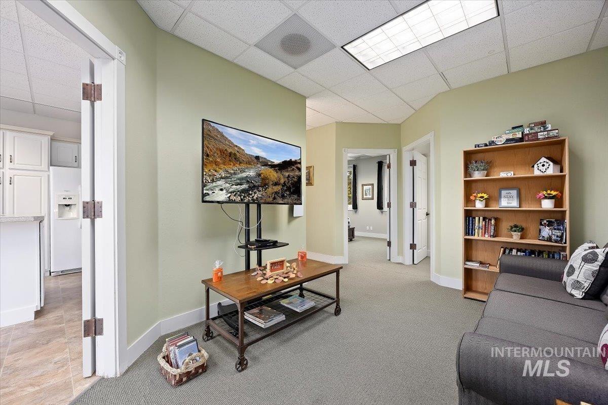Living room featuring a paneled ceiling and light colored carpet
