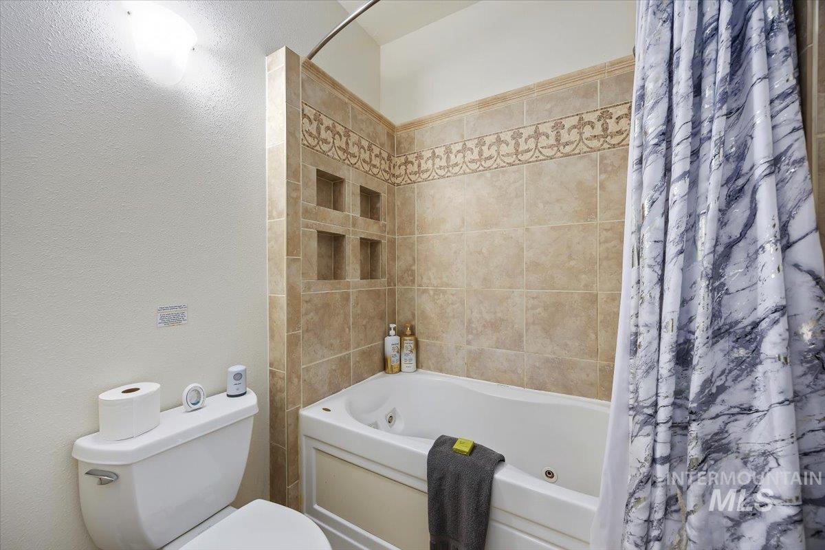 Bathroom featuring a combined bath / shower with jetted tub and a textured wall