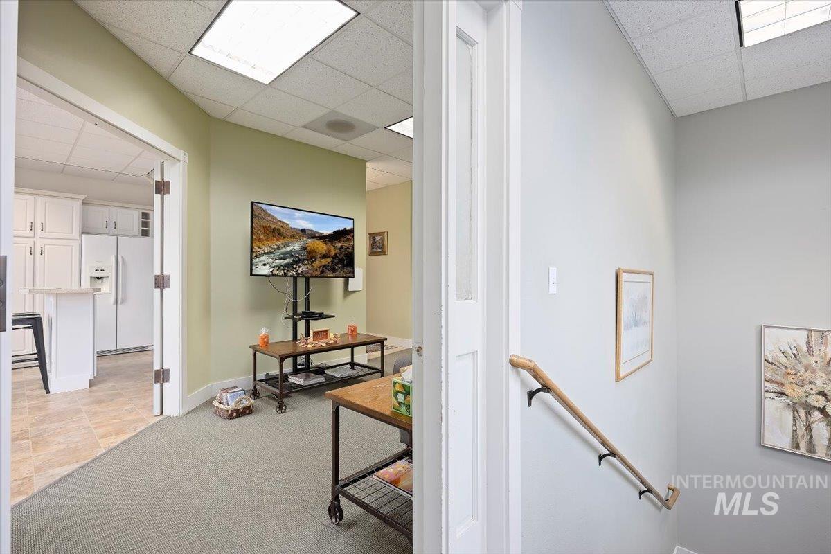 Hallway with an upstairs landing, a paneled ceiling, and light carpet