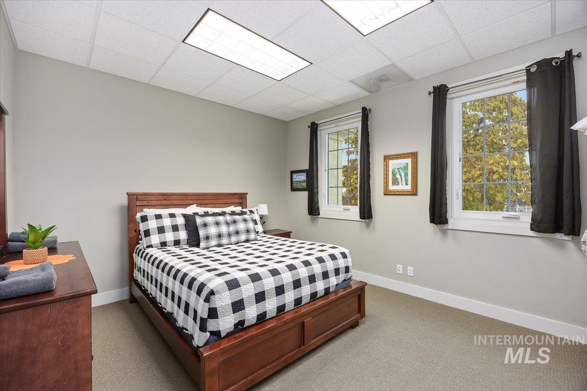 Carpeted bedroom with a drop ceiling and baseboards