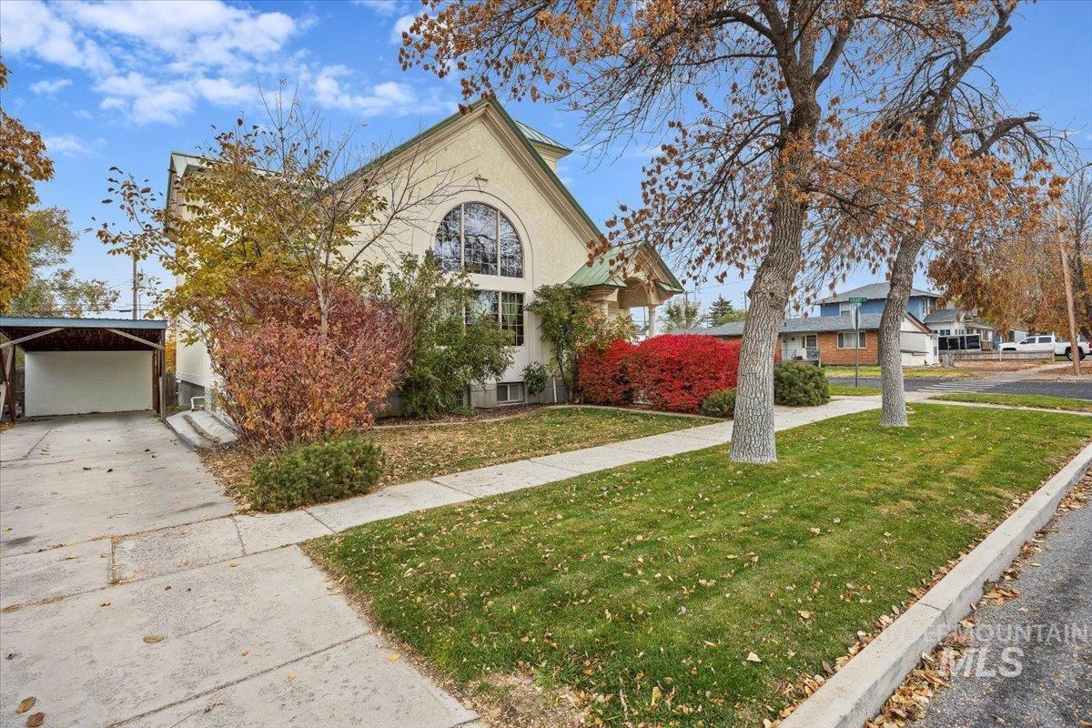 Obstructed view of property featuring a front yard, driveway, a carport, and stucco siding