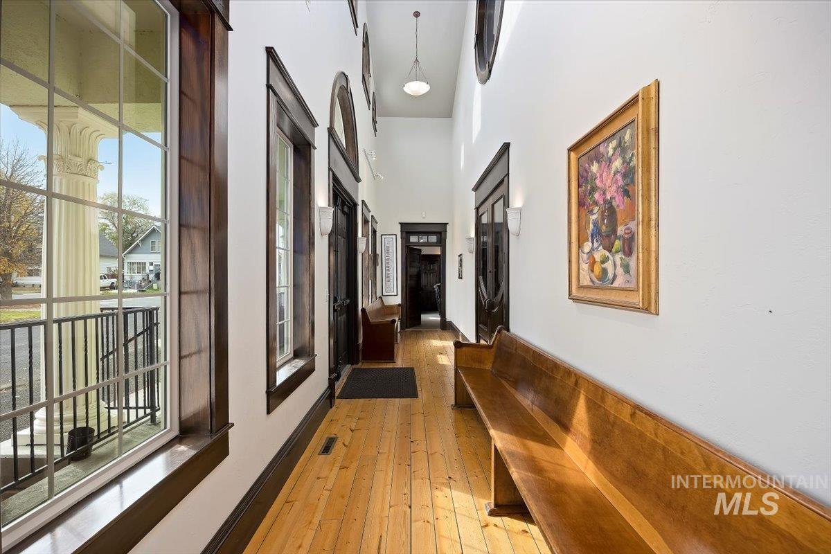 Hall featuring light wood-type flooring and a towering ceiling